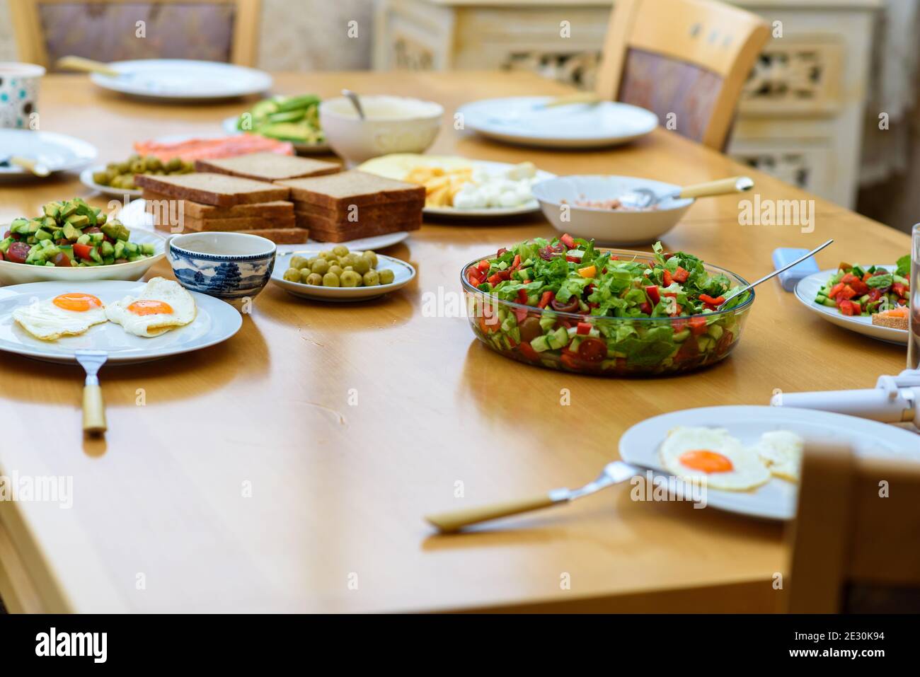 Serving of eggs, bread and salad from fresh vegetables on wooden table, healthy and organic food, breakfast with friends Stock Photo