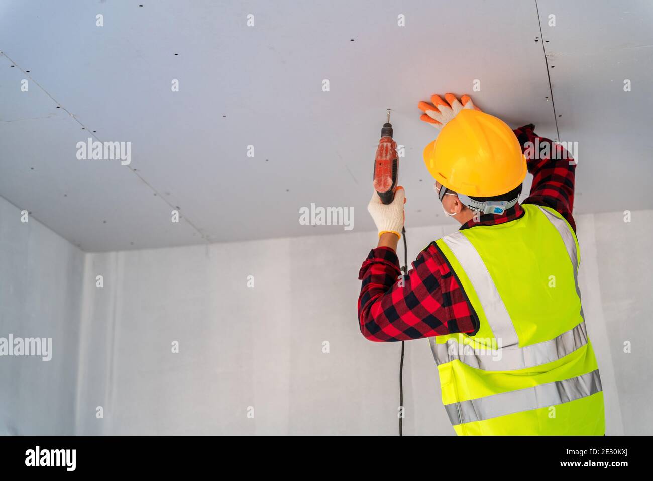 Construction worker used electric drill installation ceiling Stock
