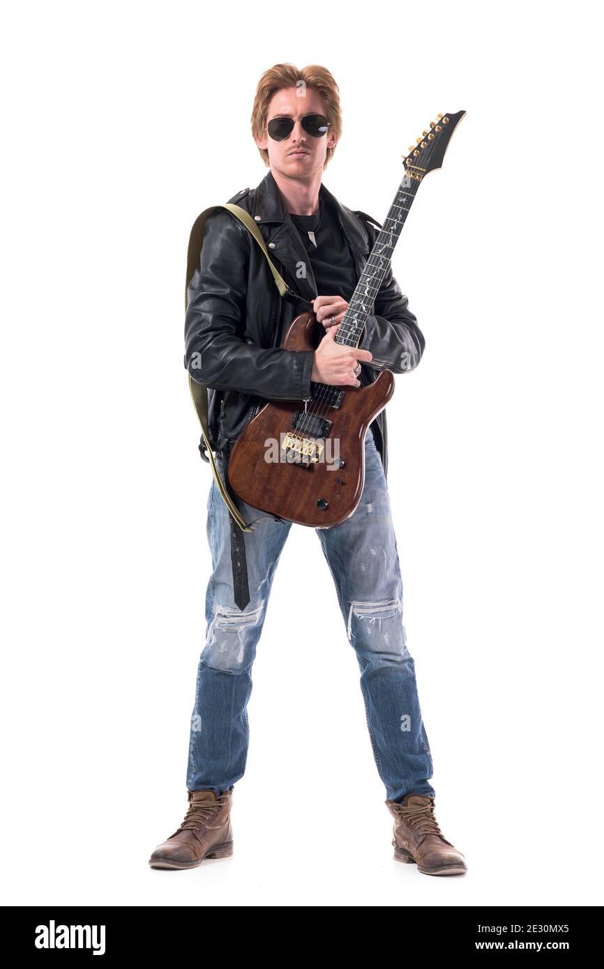 Macho stylish rocker with electric guitar and sunglasses wearing leather jacket and jeans. Full body isolated on white background. Stock Photo
