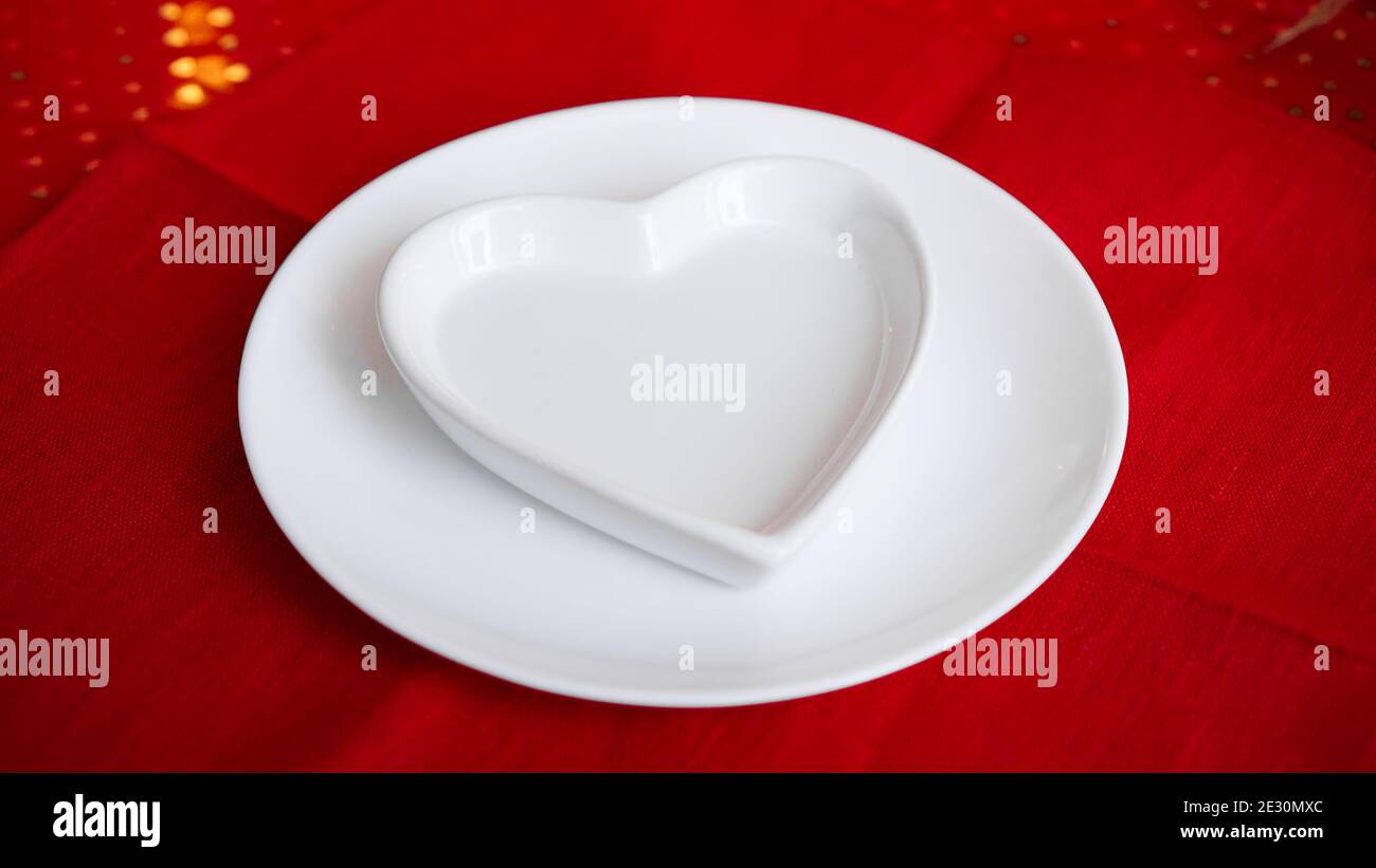 Heart shaped white plate on red background Stock Photo