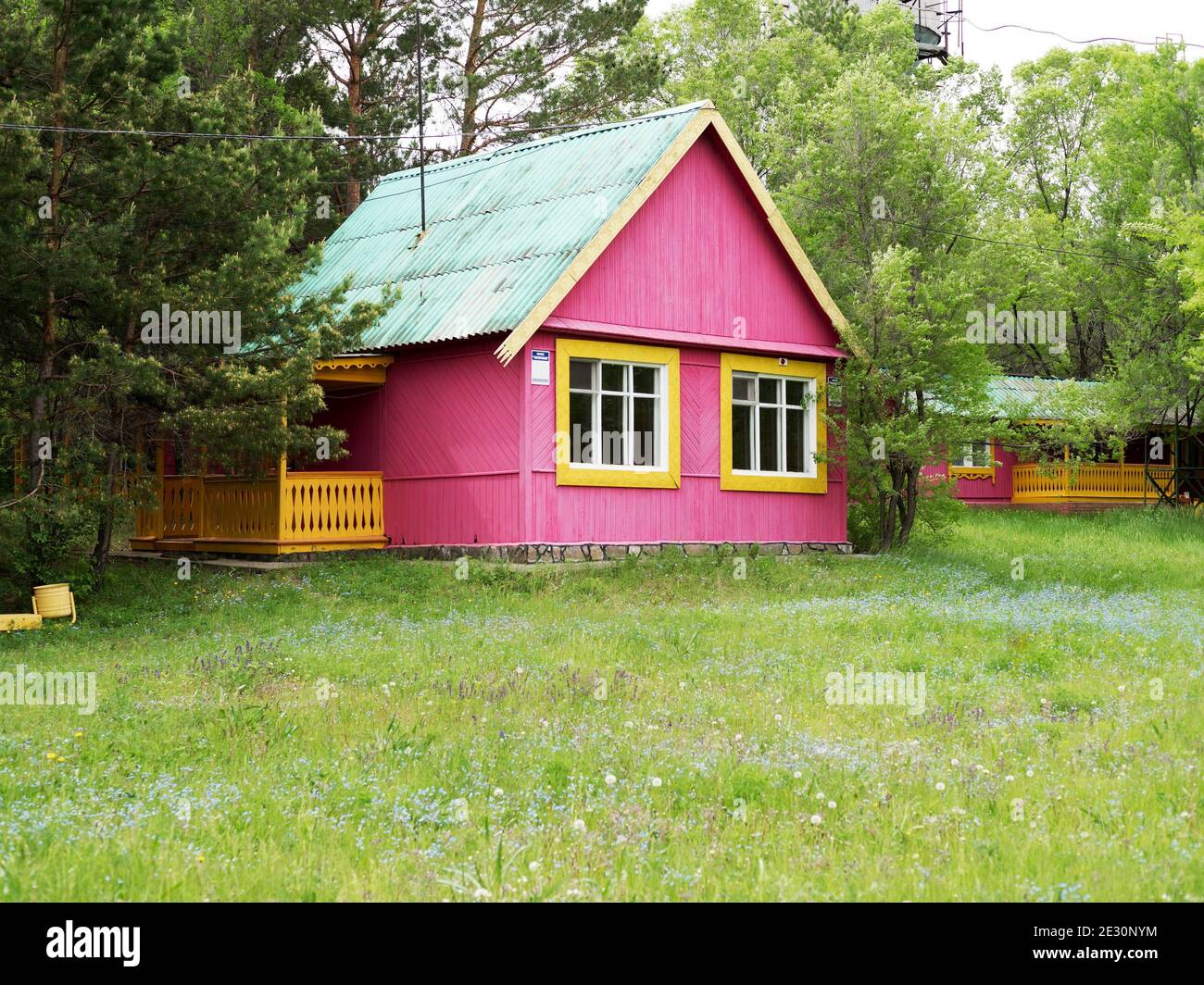 A small wooden guest house stands in the garden among the trees on a summer day. Stock Photo