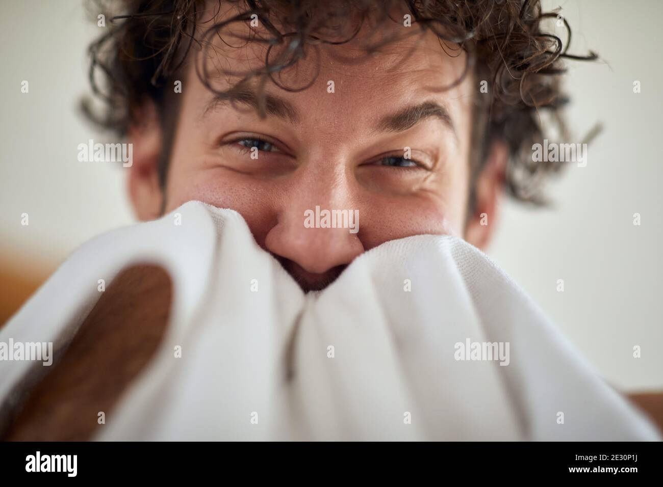 A young cheerful man wipes his face after shaving at the bathroom. Routine, morning, hygiene Stock Photo
