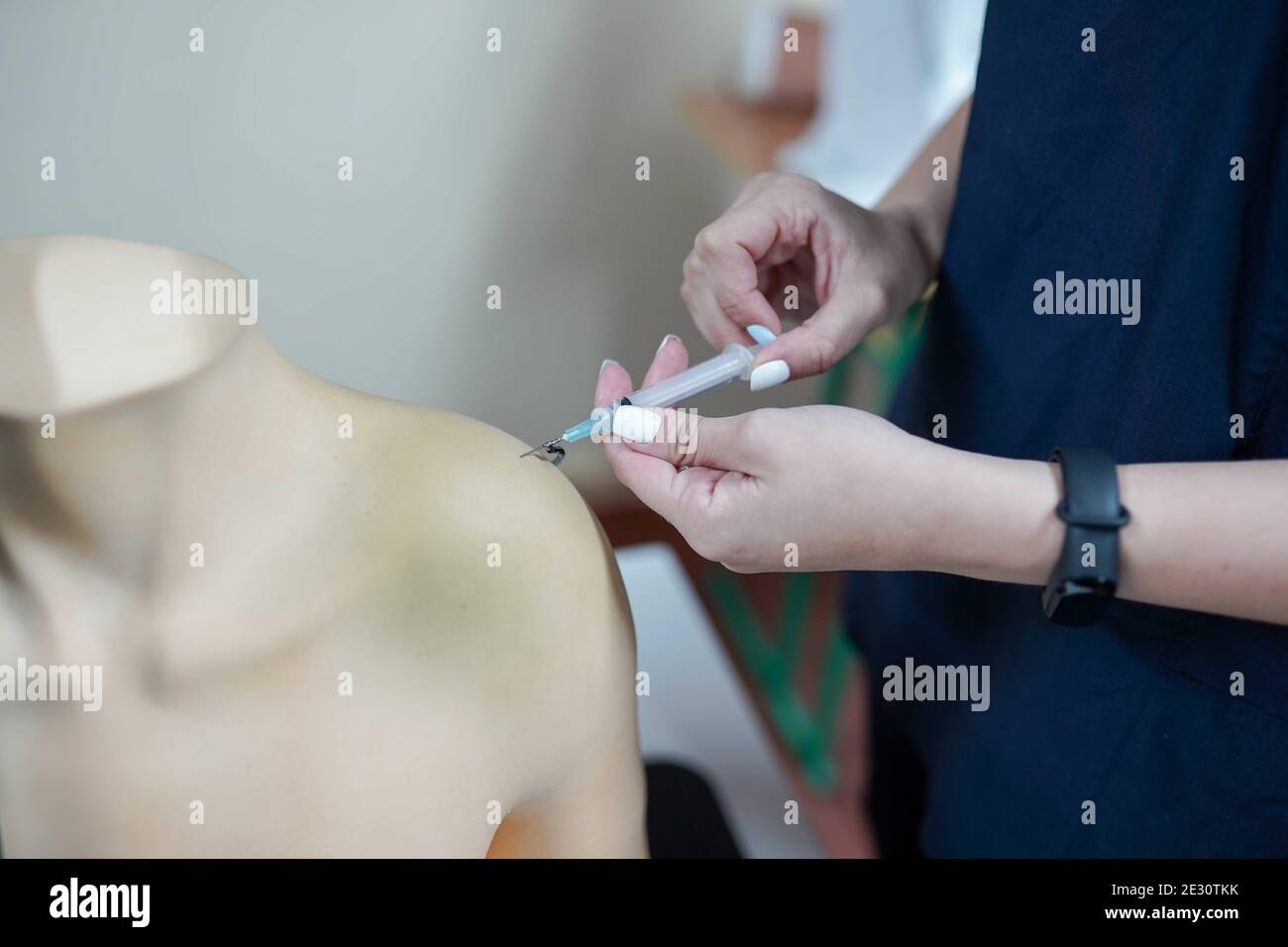 Nursing student practicing blood taking on mannequin hand under instructor supervision . medical background Stock Photo