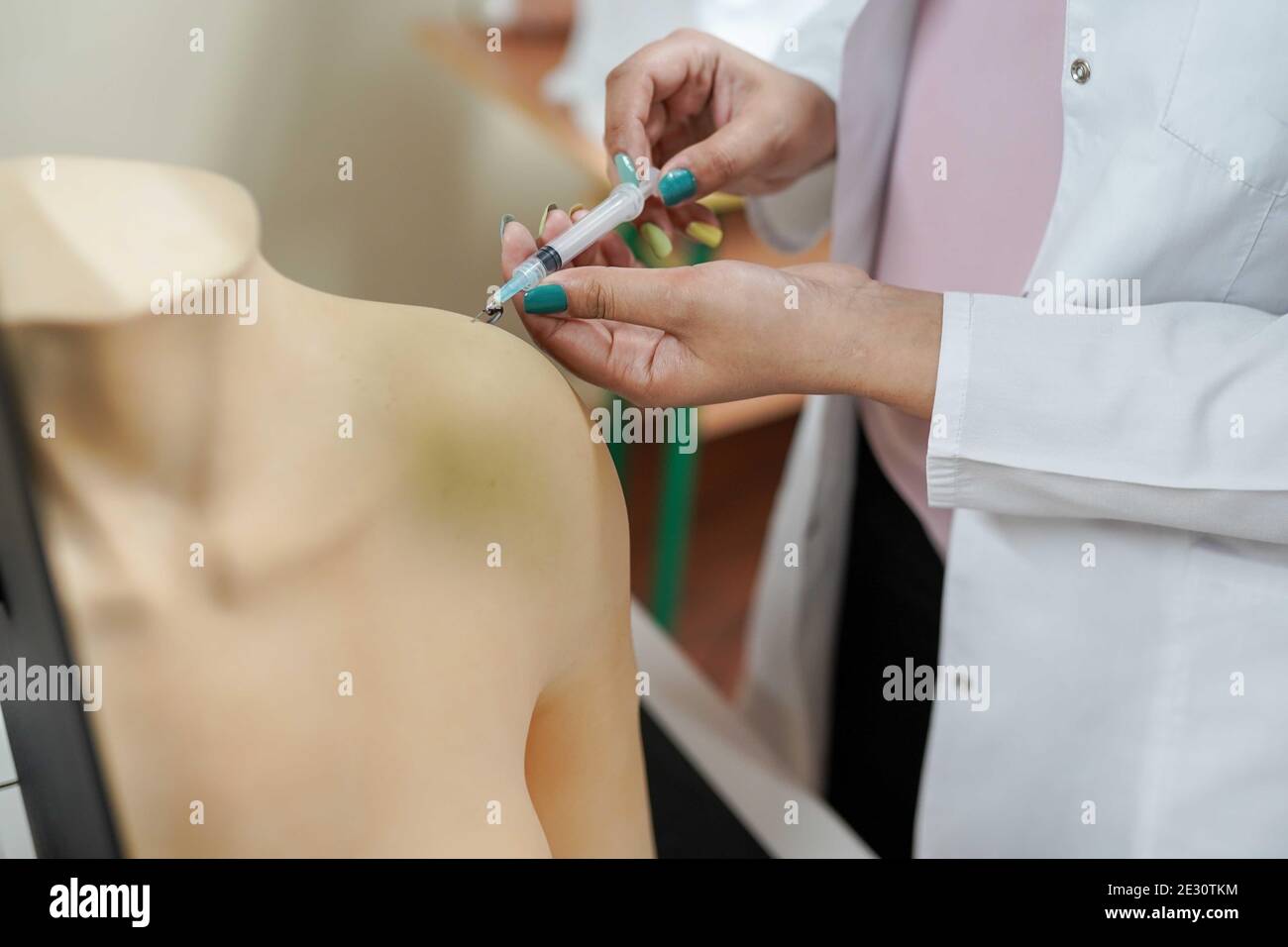 medical background.Nursing student practicing blood taking on mannequin hand under instructor supervision . Stock Photo