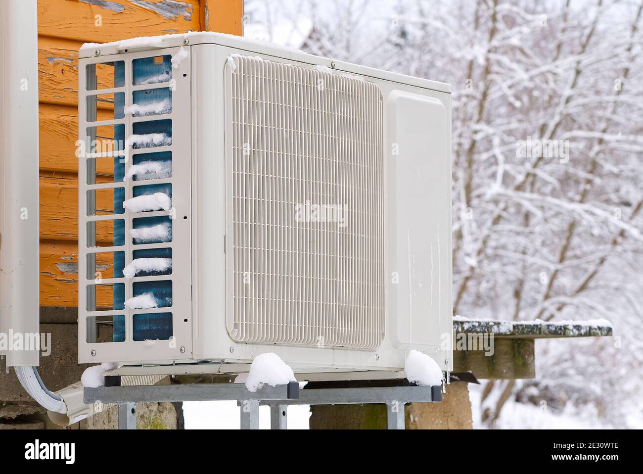 Air to water heat pump near an old wooden house in winter. air water