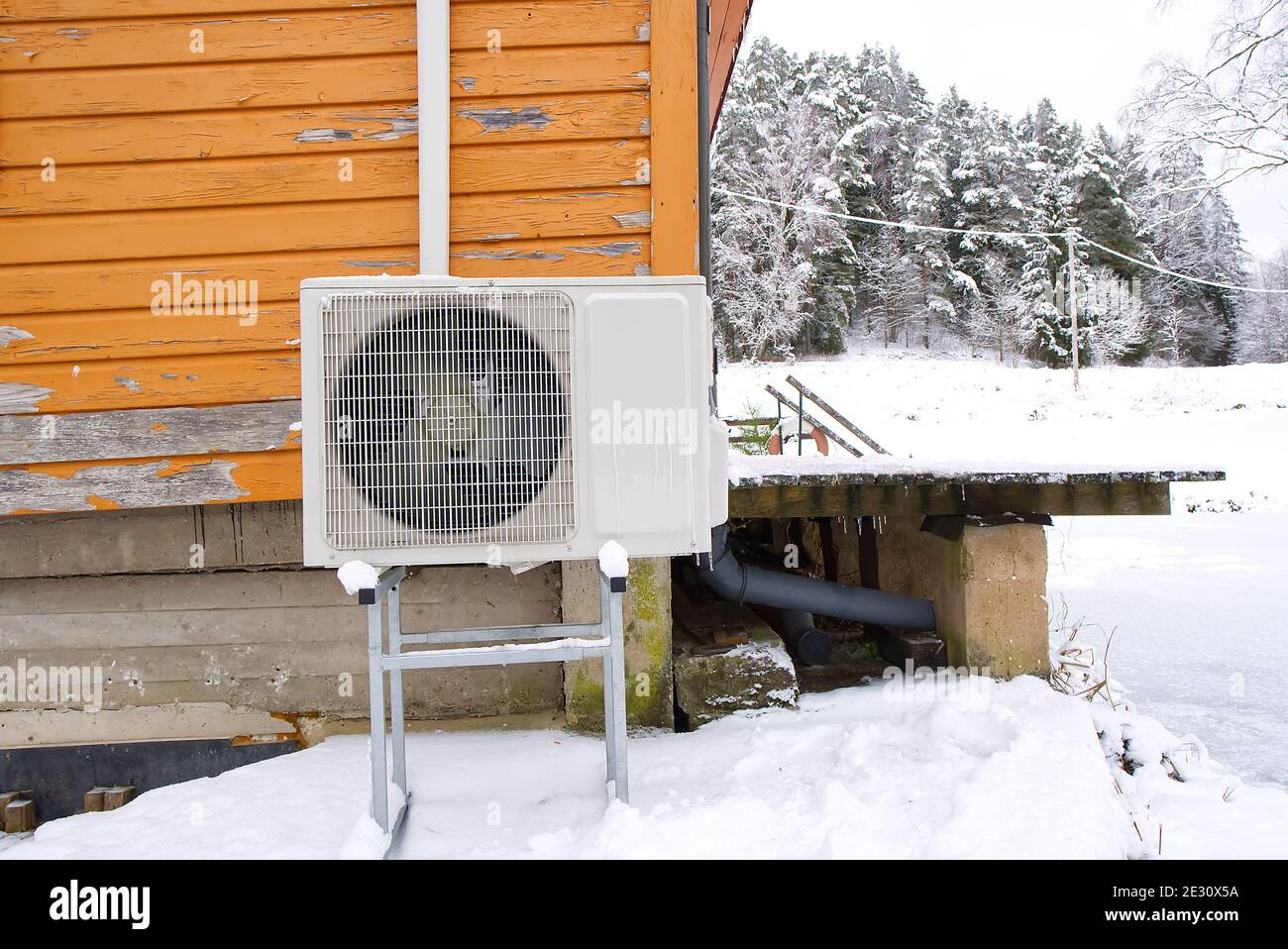 Air to water heat pump near an old wooden house in winter. air water  heatpump close up Stock Photo - Alamy