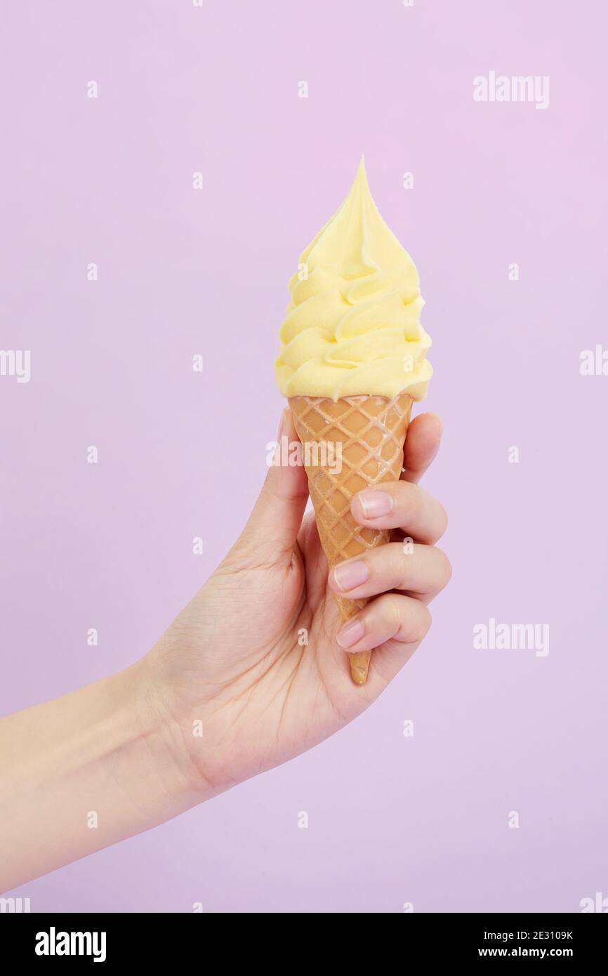 Female's hand holding delicious soft ice cream in a crispy waffle cone ...