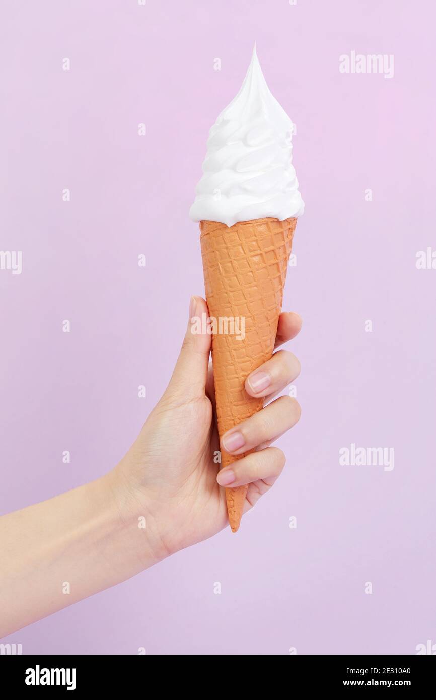 Female's hand holding delicious soft ice cream in a crispy waffle cone ...