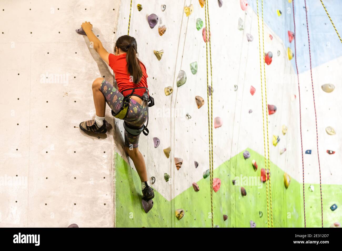 Sporty little girl climbing artificial boulder on practical wall in gym  Stock Photo - Alamy