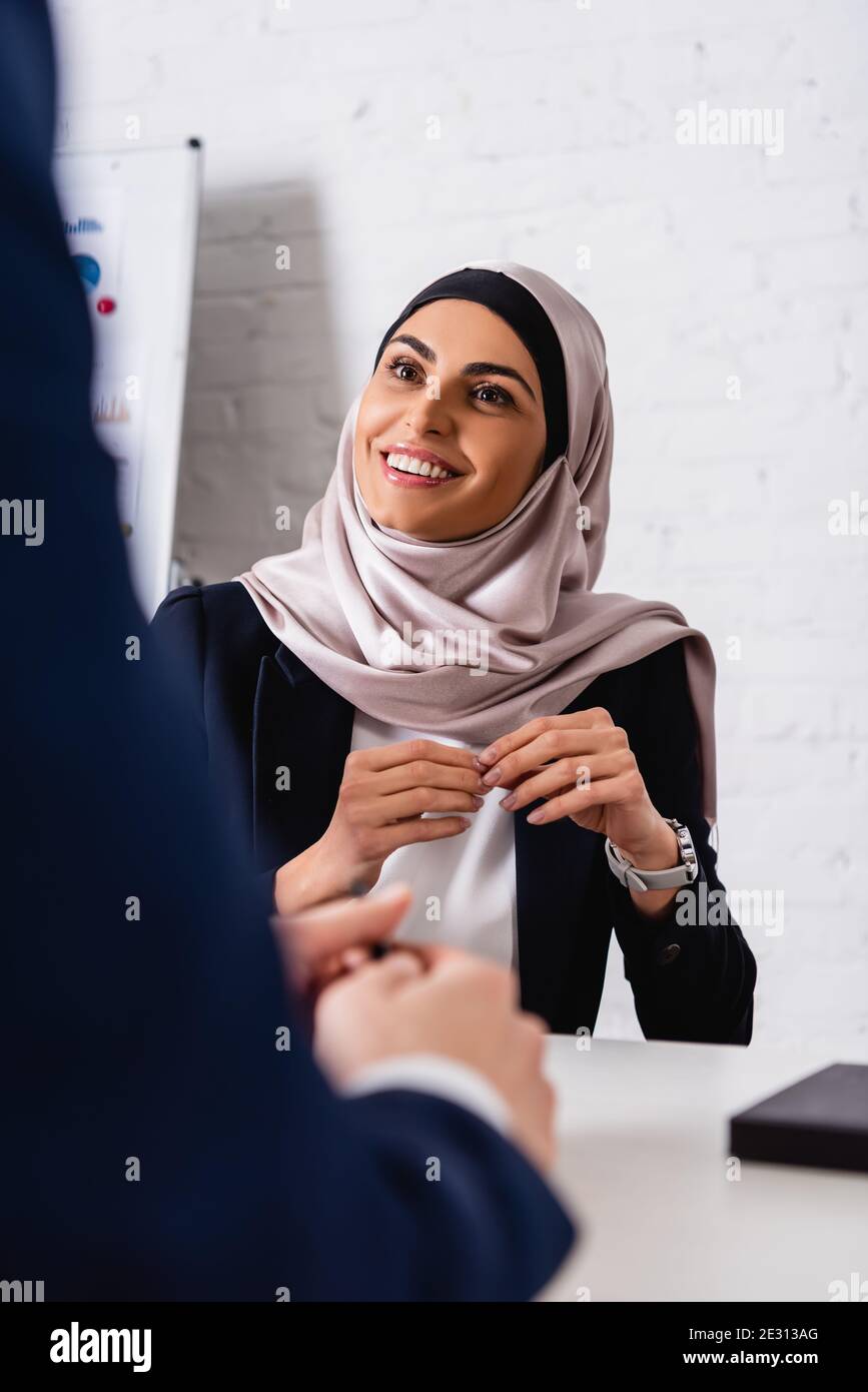 happy arabian businesswoman looking at interpreter on blurred foreground Stock Photo