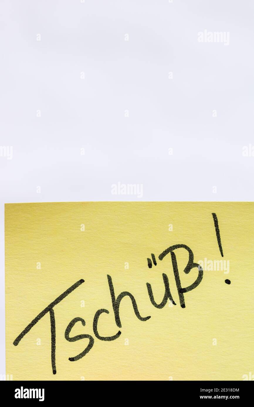 Tschuss (bye) handwriting text close up isolated on yellow paper with copy space. Stock Photo