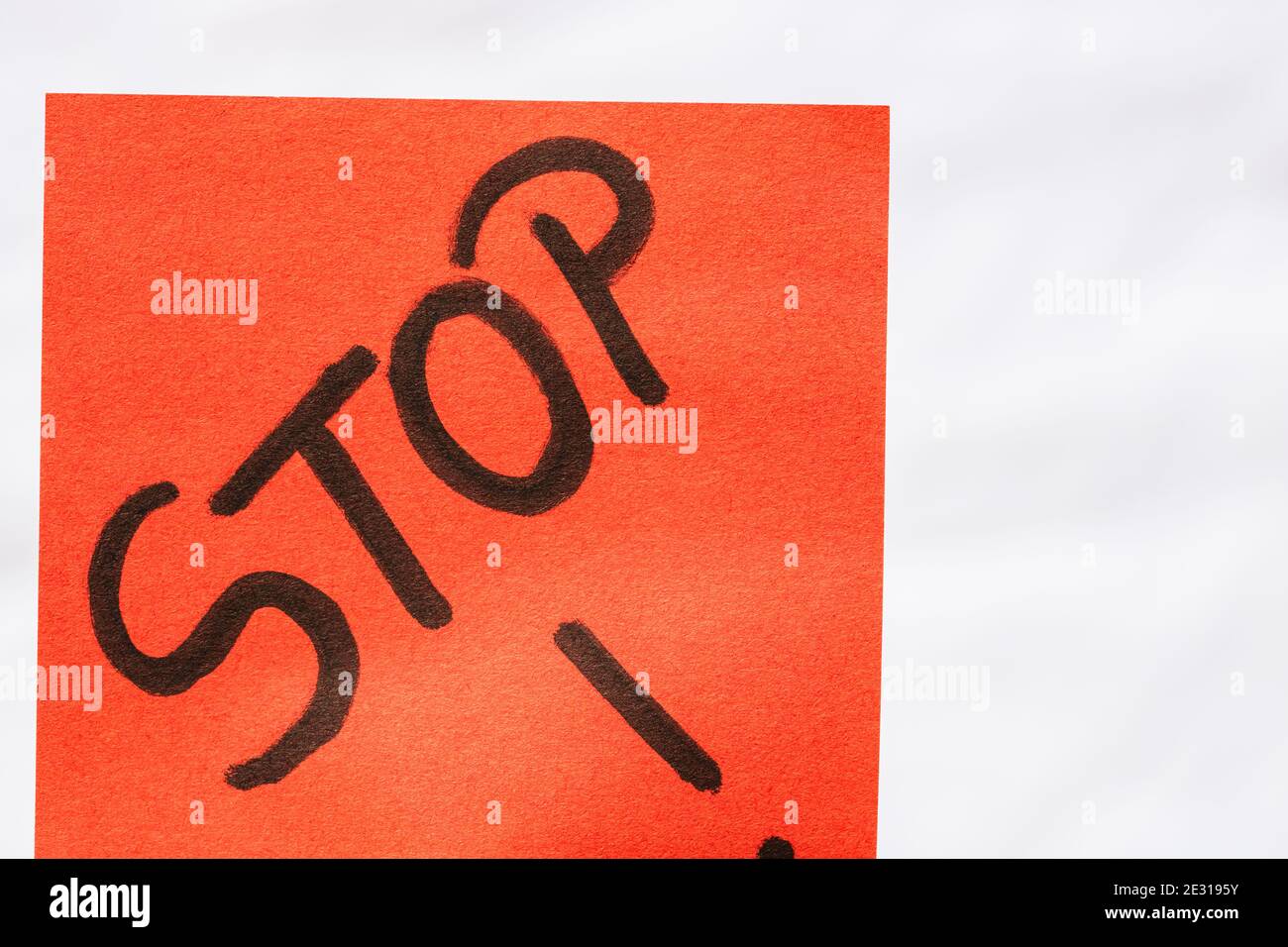 Stop handwriting text close up isolated on orange paper with copy space