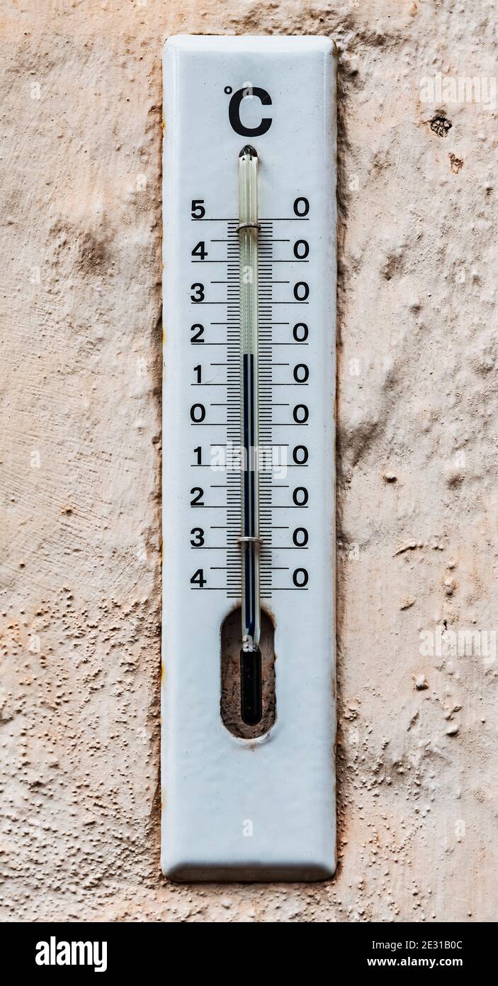 A white enamelled analogue outdoor thermometer shows the temperature of 17 degrees Celsius Stock Photo