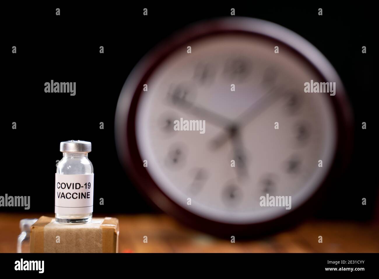 Covid-19 coronavirus vaccination bottle with clock Behind, concept of covid-19 vaccine immunity duration and second dose time frame Stock Photo