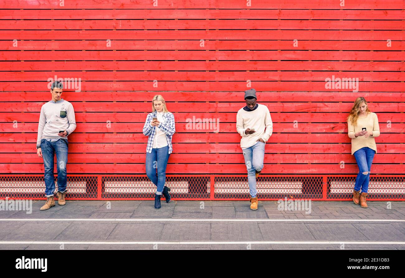 Group of multiracial fashion friends using smartphone with red wood background - Technology addiction in urban lifestyle Stock Photo