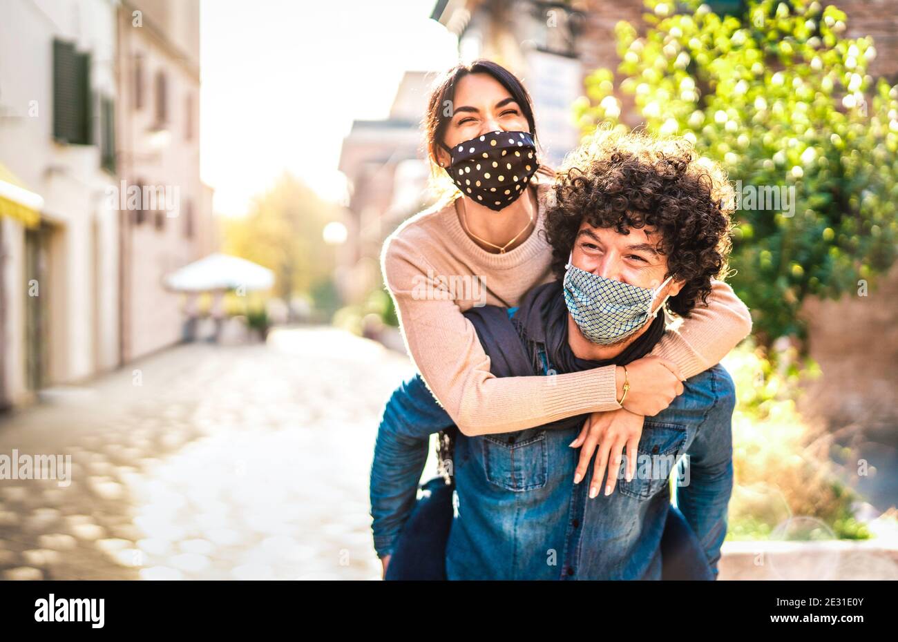 Happy couple of lovers enjoying time outdoor at Valentines day - Handsome guy with nice girl on piggy back moment - New normal love concept Stock Photo