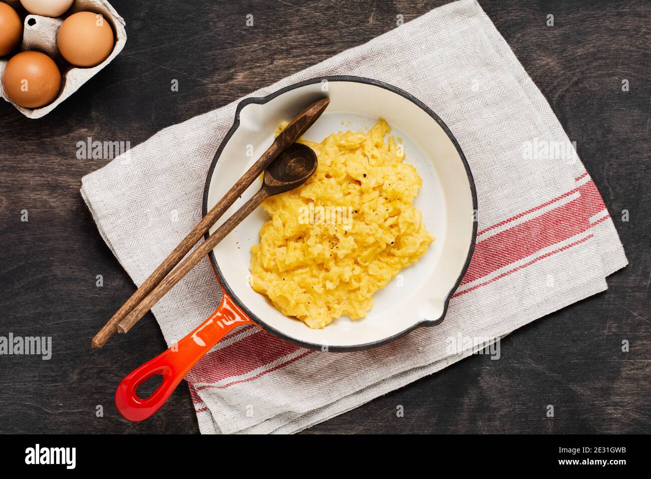 Scrambled eggs for breakfast on frying pan, dark wooden table ...