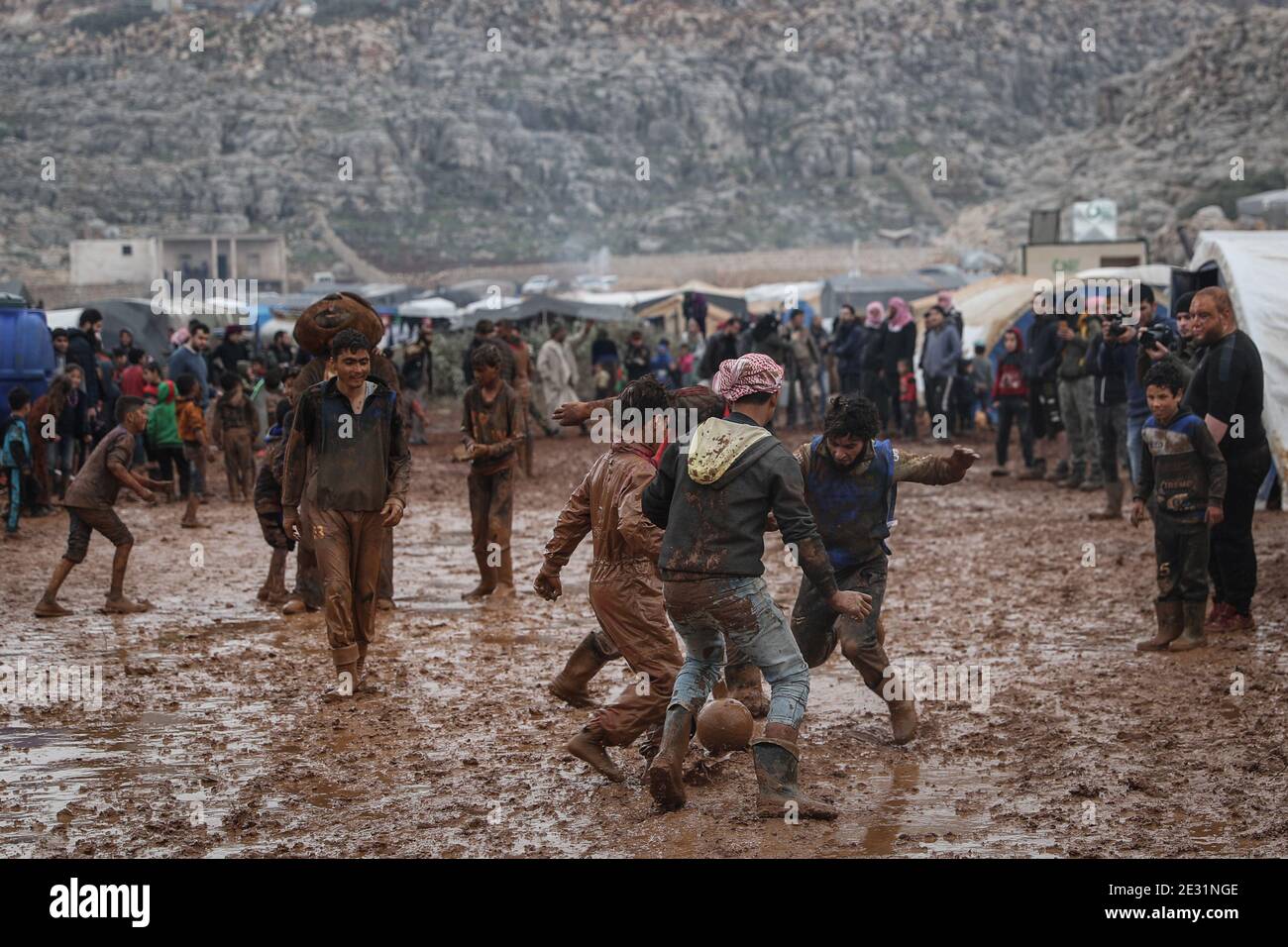 Sarmada, Syria. 16th Jan, 2021. Syrians play football in the mud during a sports competition organized by volunteers at the Baraem camp for internally displaced people. Credit: Anas Alkharboutli/dpa/Alamy Live News Stock Photo