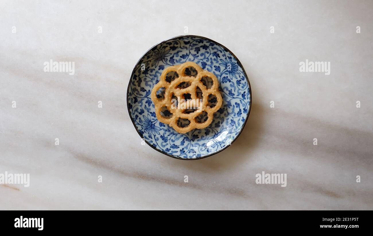 One honeycomb cookie on a plate. Also called kuih loyang in Malaysia, it is a popular deep-fried snack during festivals. Stock Photo
