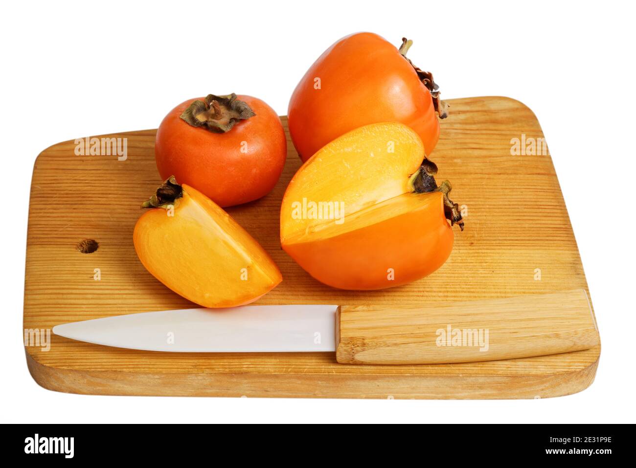 Persimmons on wooden kitchen cutting board isolated on white Stock Photo