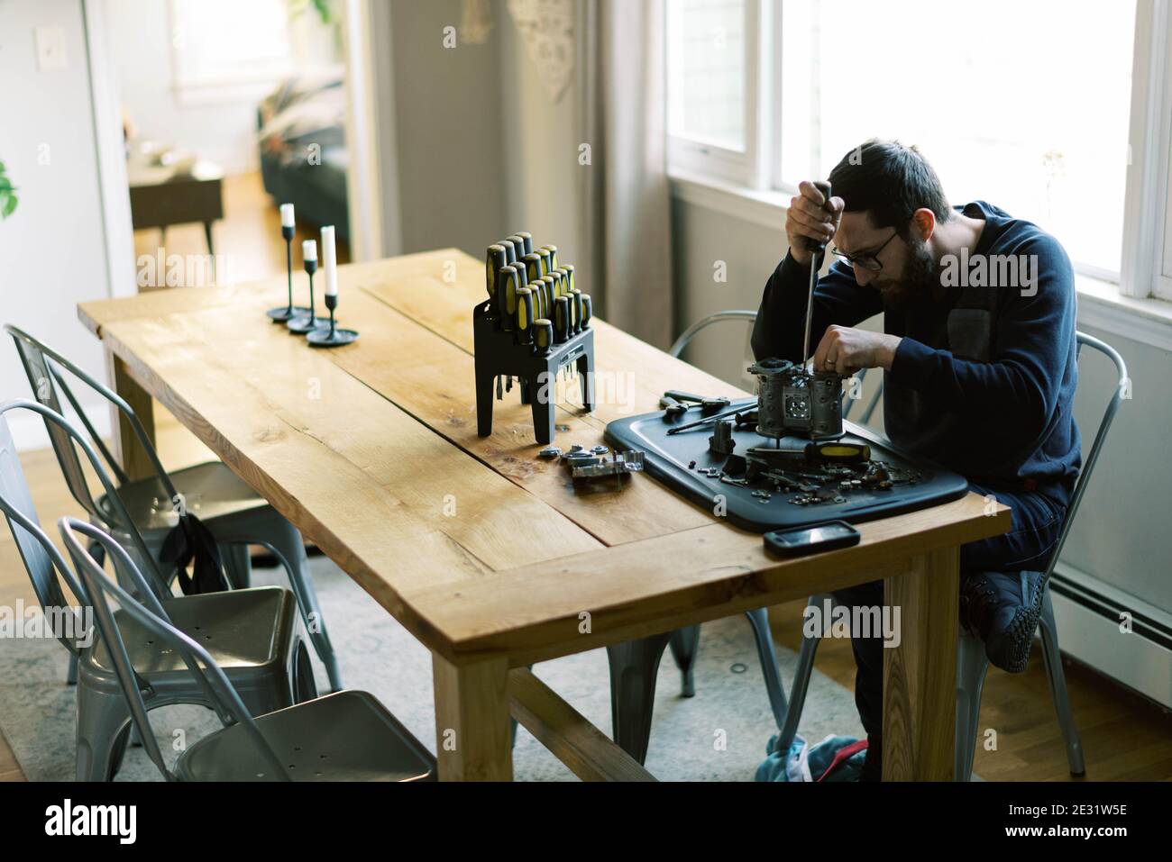 Young millennial mechanic man taking apart carburetor for restoration