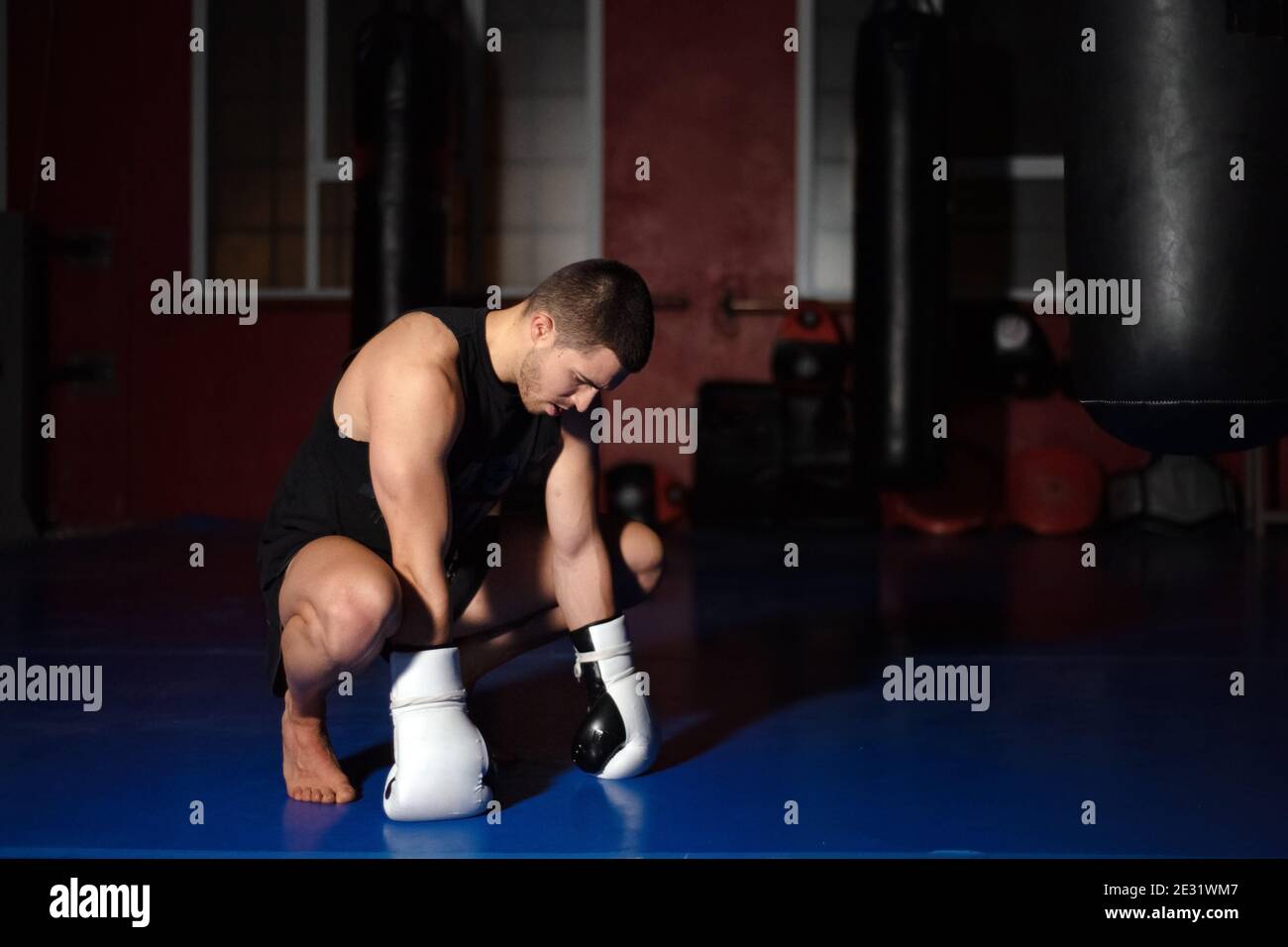 Kickboxing fighter in boxing gloves standing on knees. High quality