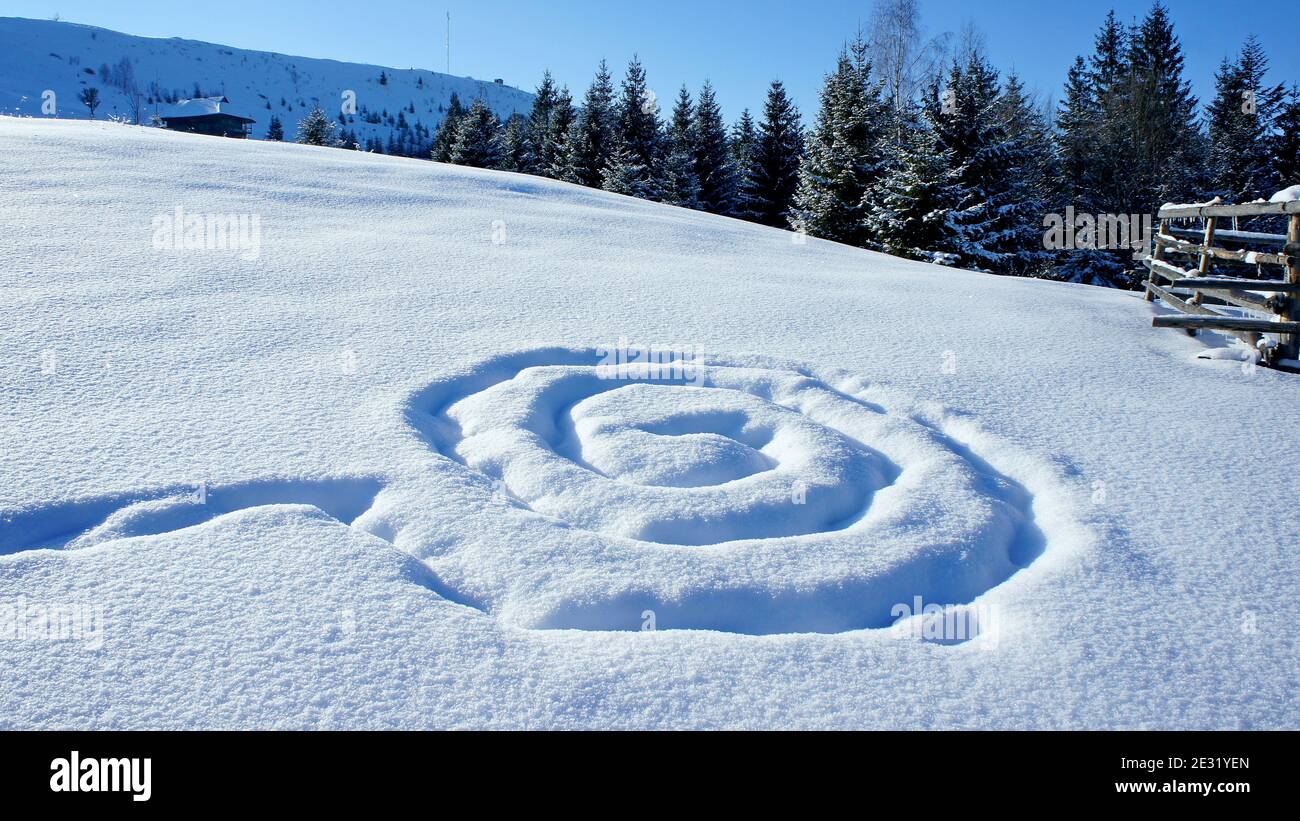 footprints in the snow in the form of a spiral pattern on snowy slope Stock Photo