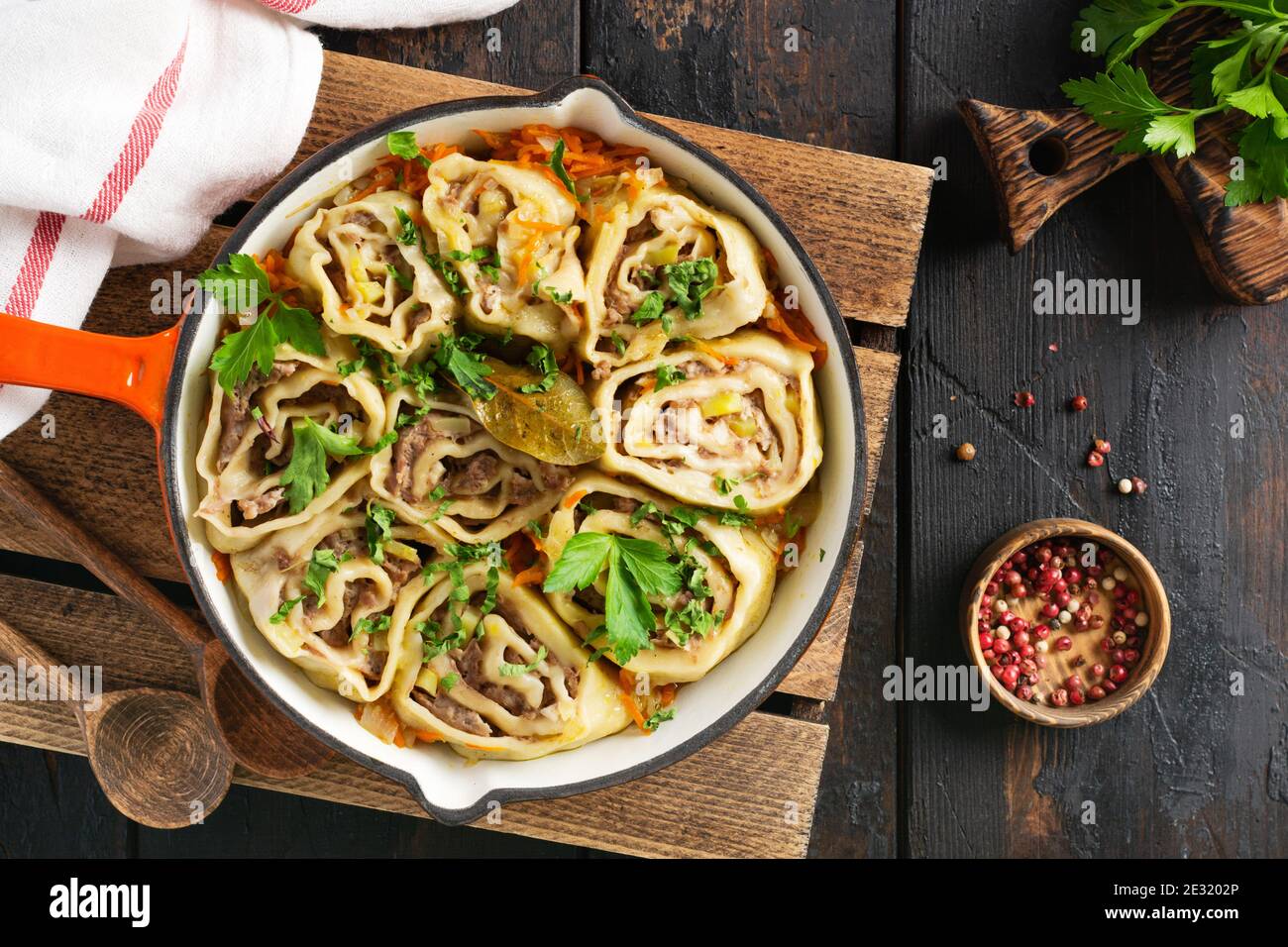 Meat dough rolls with meat or 'lazy dumplings' in a cast-iron pan on an old rustic wooden background. Top view. Stock Photo