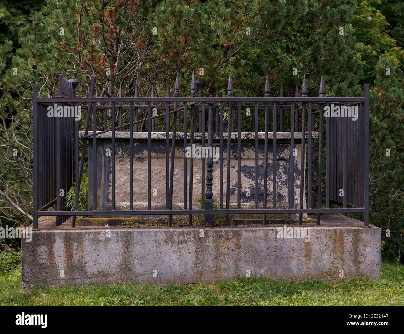 Old dark grave crypt surrounded by wrought iron fence. Crypt sits on a ...