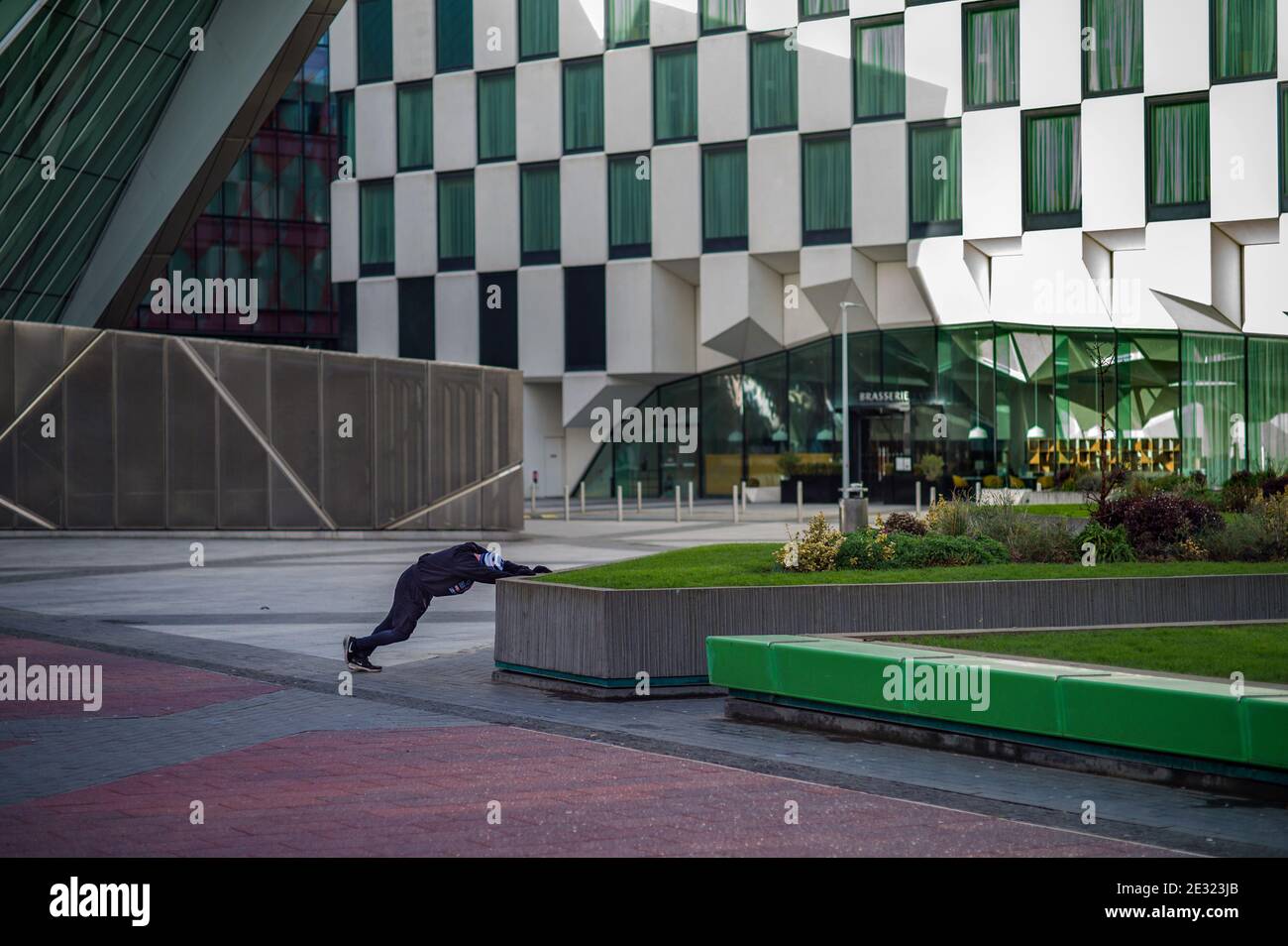A jogger in Dublin Docklands stretches in the plaza after a run. Stock Photo