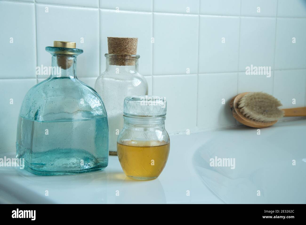 Bubble bath and bath salts. Bottles and brush on a bathtub with soft light from a window. Stock Photo