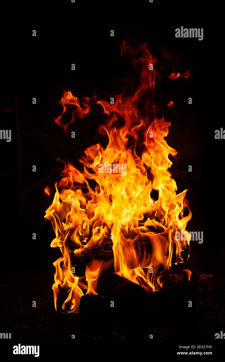 Close-up on a bright flame of a bonfire at night on a black background. Dark mood photo. Concept for outdoor recreation, travel, activity. Vertical fo Stock Photo