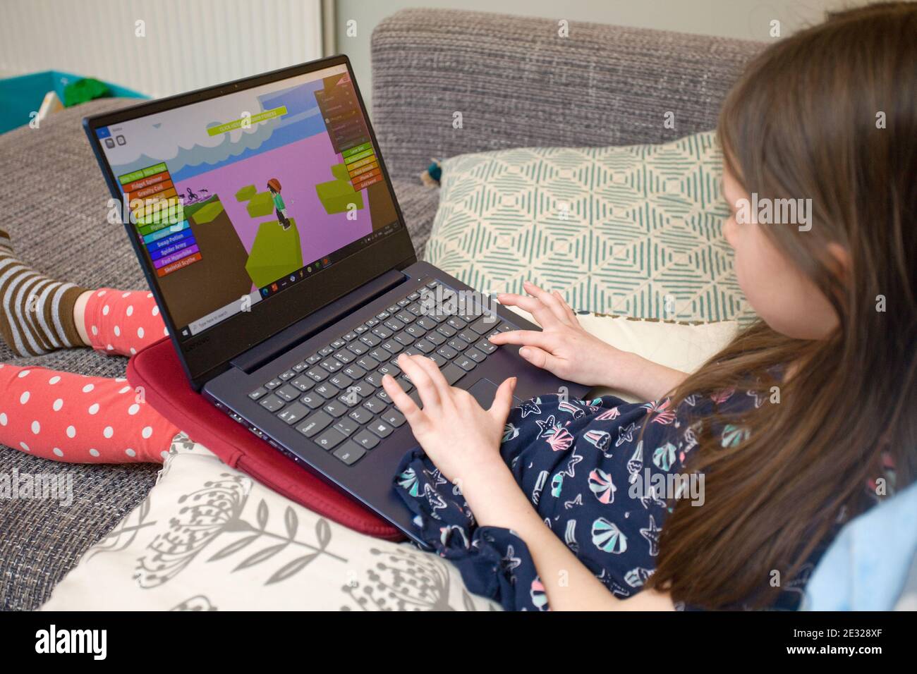 7 year old girl playing Roblox on laptop computer. England Stock Photo