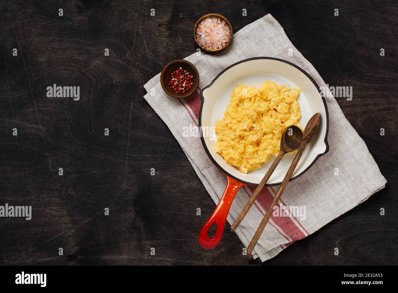 Scrambled eggs for breakfast on frying pan, dark wooden table ...