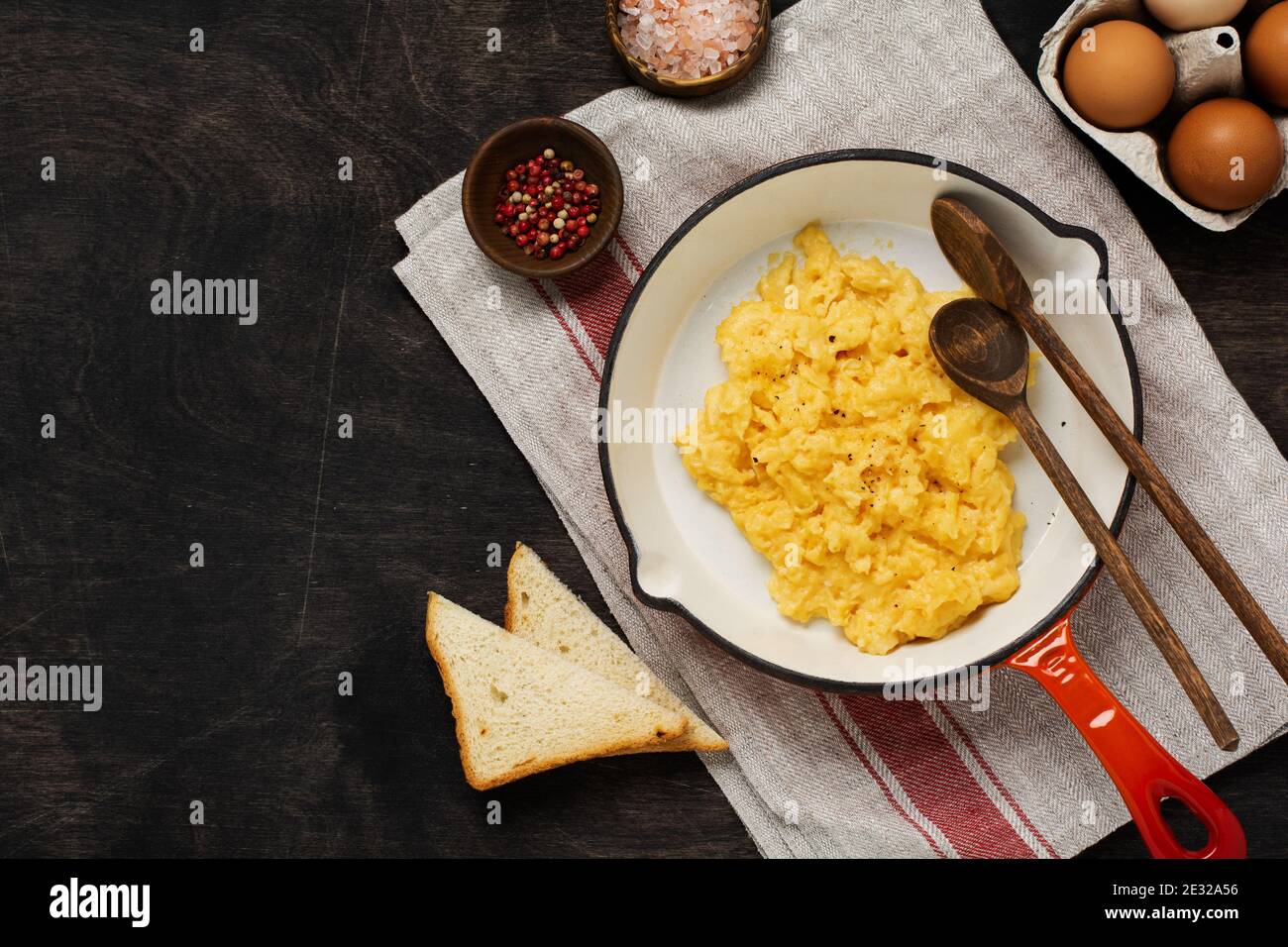 Scrambled eggs for breakfast on frying pan, dark wooden table ...