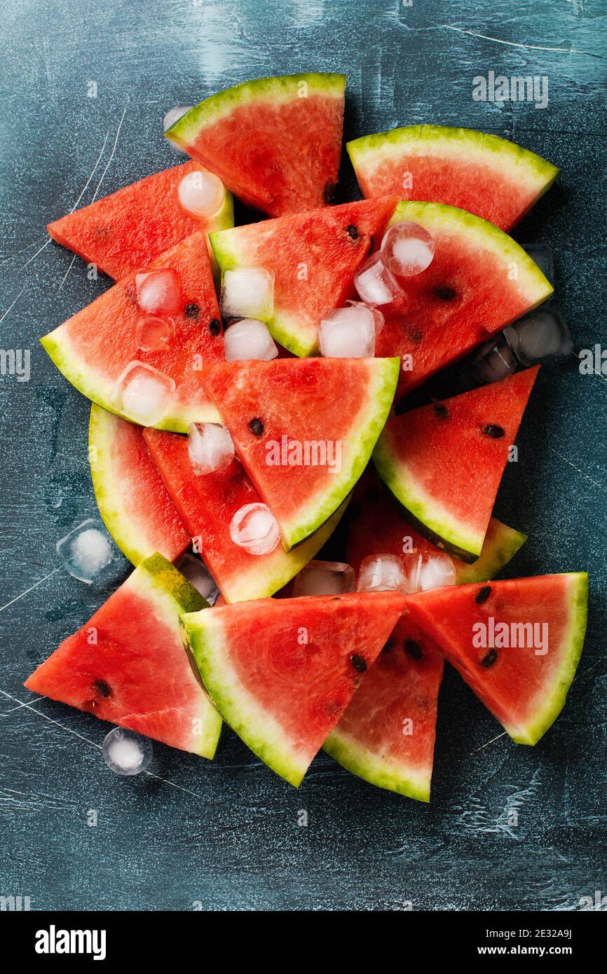 Slices of fresh watermelon with ice on a blue concrete background ...