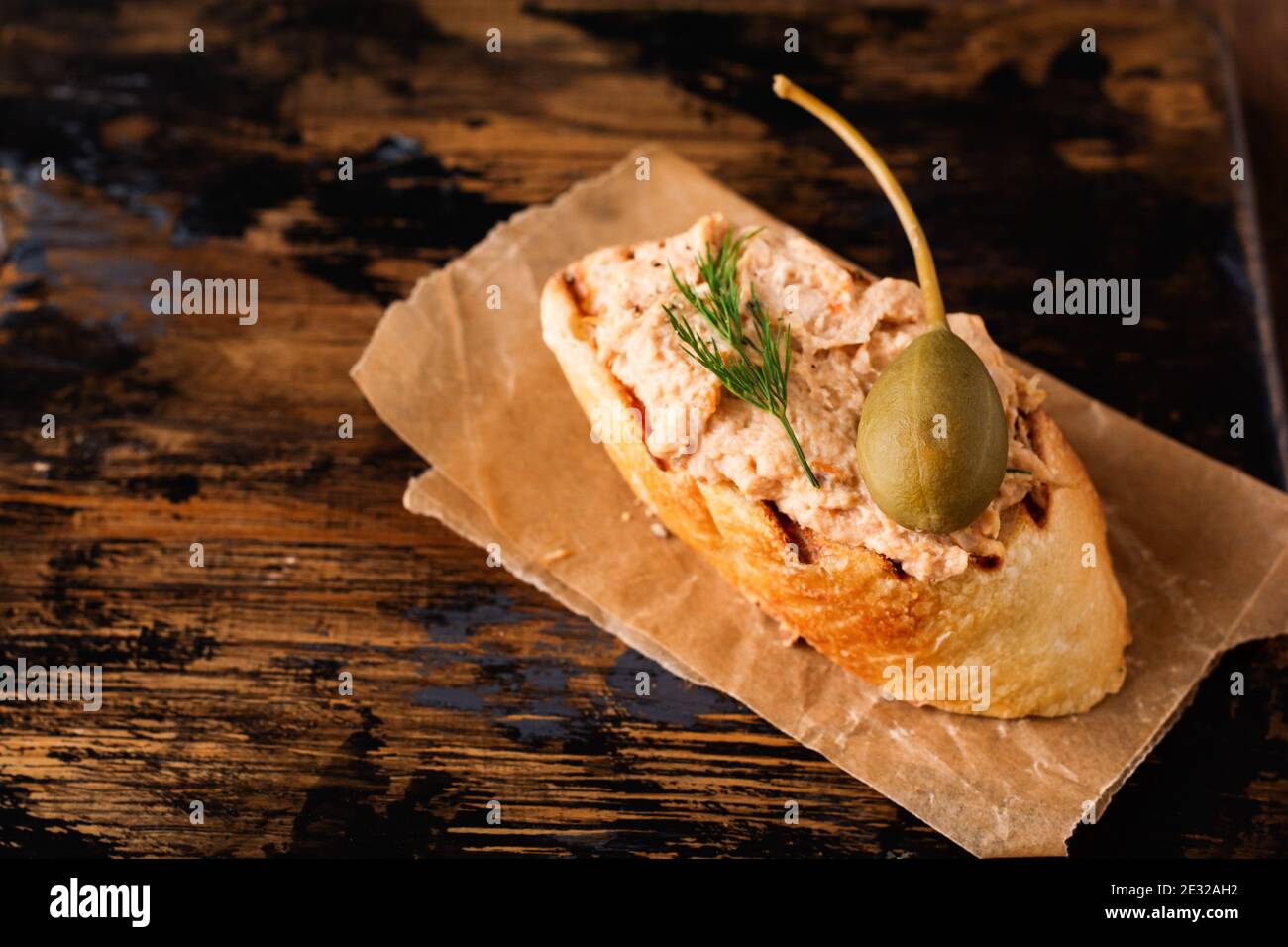 Sandwich with chicken pate with caper on a dark old board background