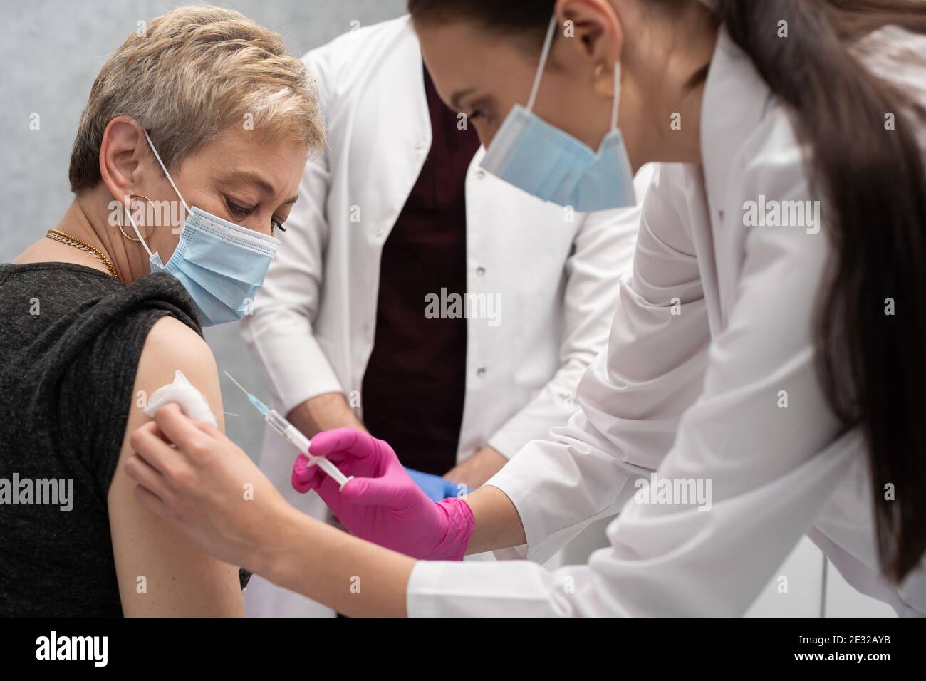 A young nurse injects a woman in her 50s with a new COVID19 vaccine. An ...