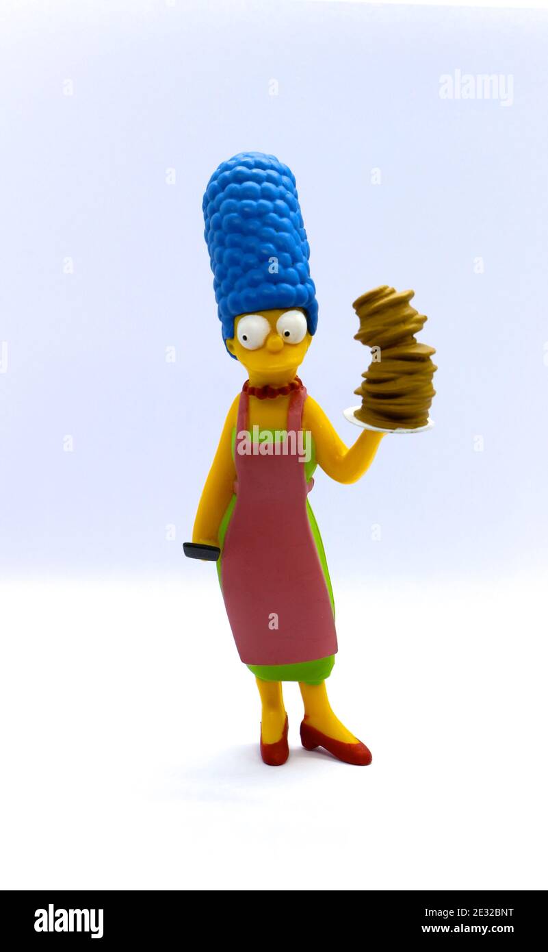 Photo of a Ceramic collectors model of Marge Simpson from the Simpsons standing holding a tall pile of pancakes on a white background Stock Photo