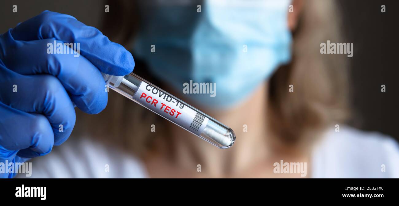 Coronavirus swab collection kit in doctor hands, panoramic view of woman in medical mask holding tube of COVID-19 PCR test. Concept of corona virus di Stock Photo