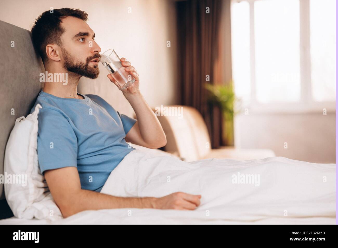 Handsome young man with beard smiling drinking water before breakfast ...