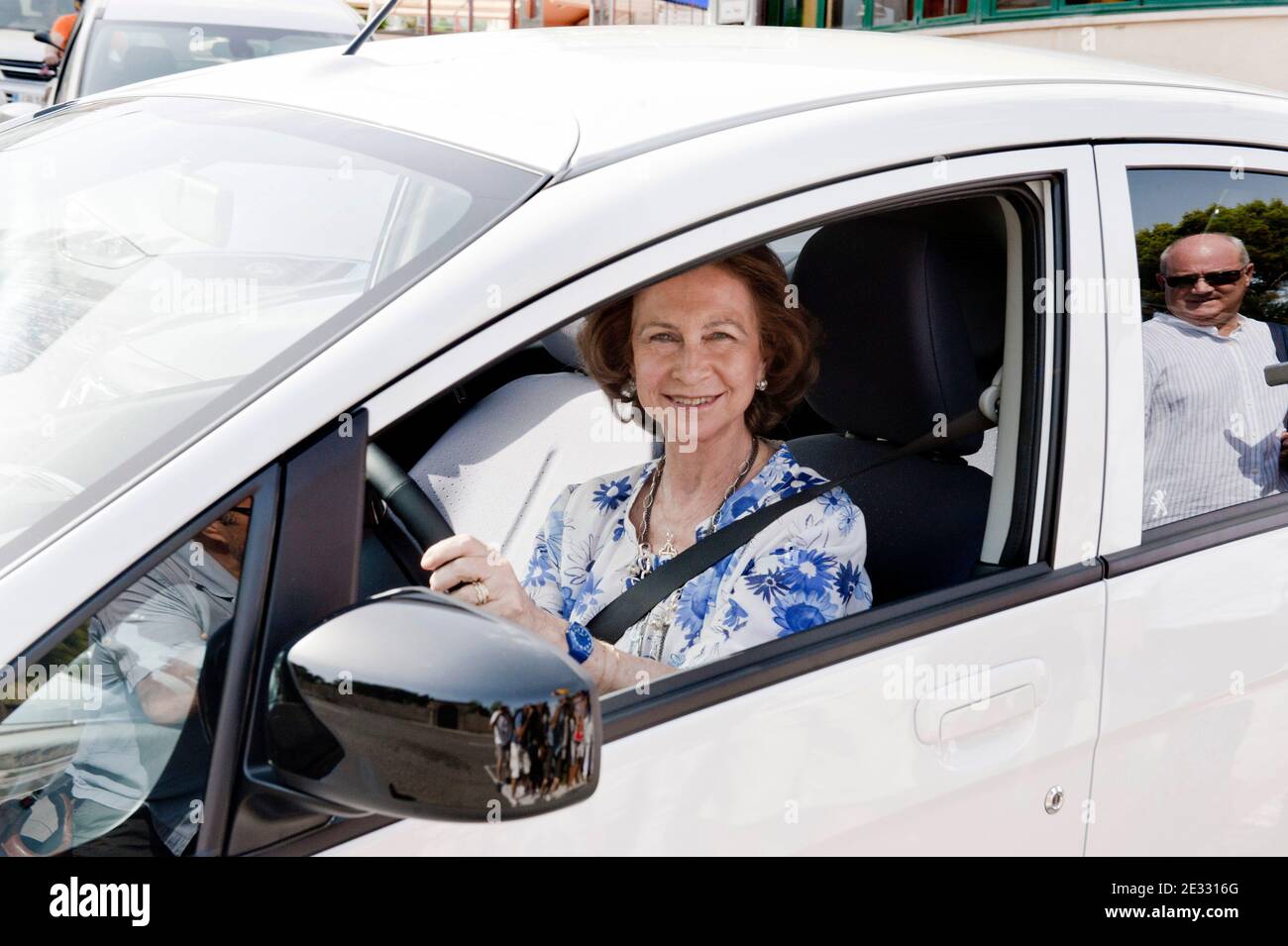 Spain's Queen Sofia drives a new electric car she just took delivery of, in Palma de Mallorca, Balearic Islands, Spain on August 11, 2010. The car, a Peugeot iON, has been lent to Queen SofÀa by the car company and was sent by air to Palma from Japan. The Queen will drive it for her private use for one month during her vacation at Marivent Palace on Mallorca. QueenæSofÀa has accepted the assignment as a show of support for electric cars as not pollutant vehicles respecting the environment. For security reasons the Queen was followed by two larger dark cars carrying her security detail. Photo b Stock Photo