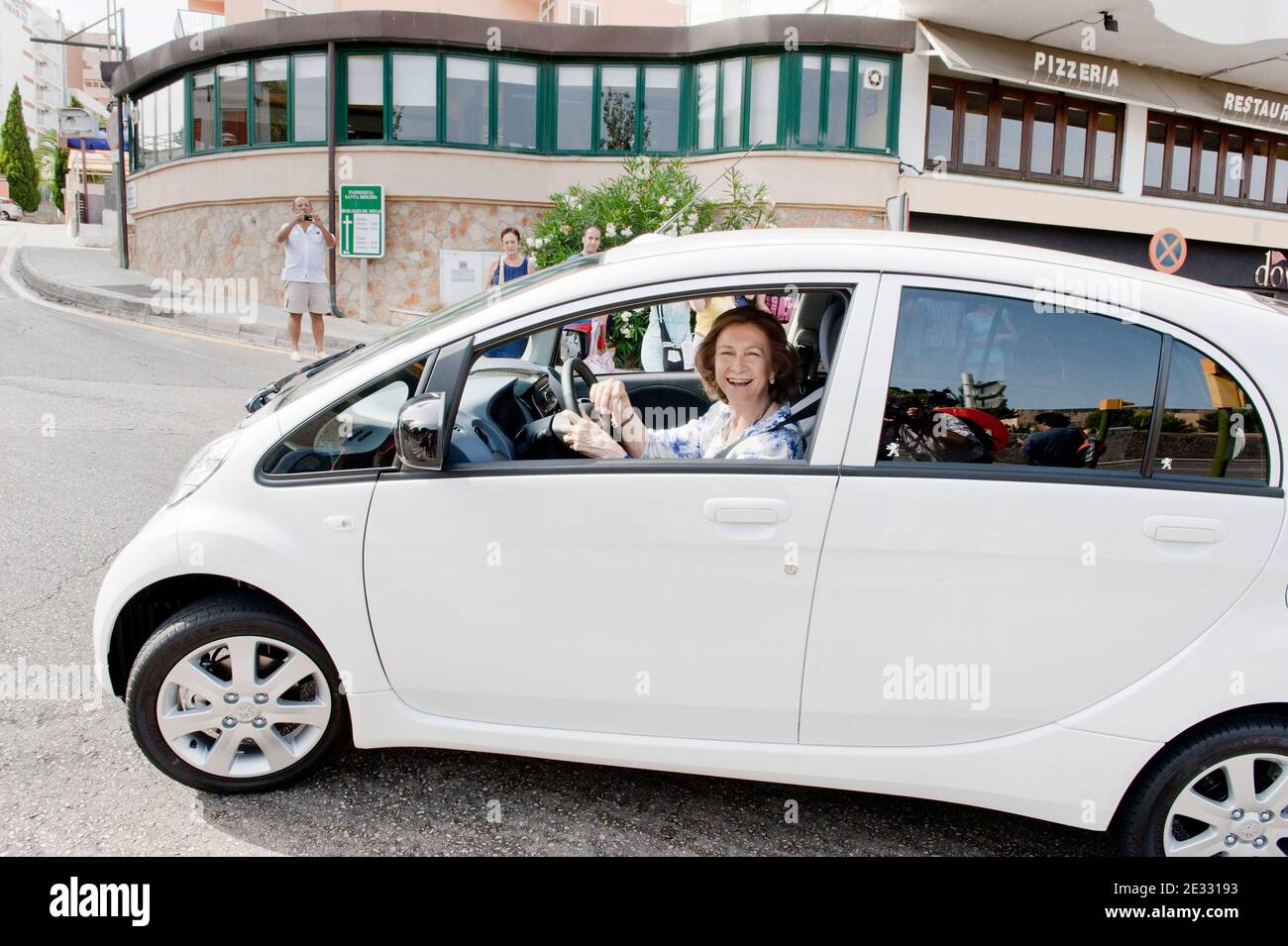 Spain's Queen Sofia drives a new electric car she just took delivery of, in Palma de Mallorca, Balearic Islands, Spain on August 11, 2010. The car, a Peugeot iON, has been lent to Queen SofÀa by the car company and was sent by air to Palma from Japan. The Queen will drive it for her private use for one month during her vacation at Marivent Palace on Mallorca. QueenæSofÀa has accepted the assignment as a show of support for electric cars as not pollutant vehicles respecting the environment. For security reasons the Queen was followed by two larger dark cars carrying her security detail. Photo b Stock Photo