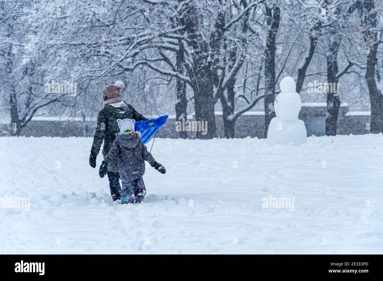 Montreal, QC, Canada - 16 January 2021: Mother  and child walking in Jeanne-Mance park during snowstorm. Stock Photo