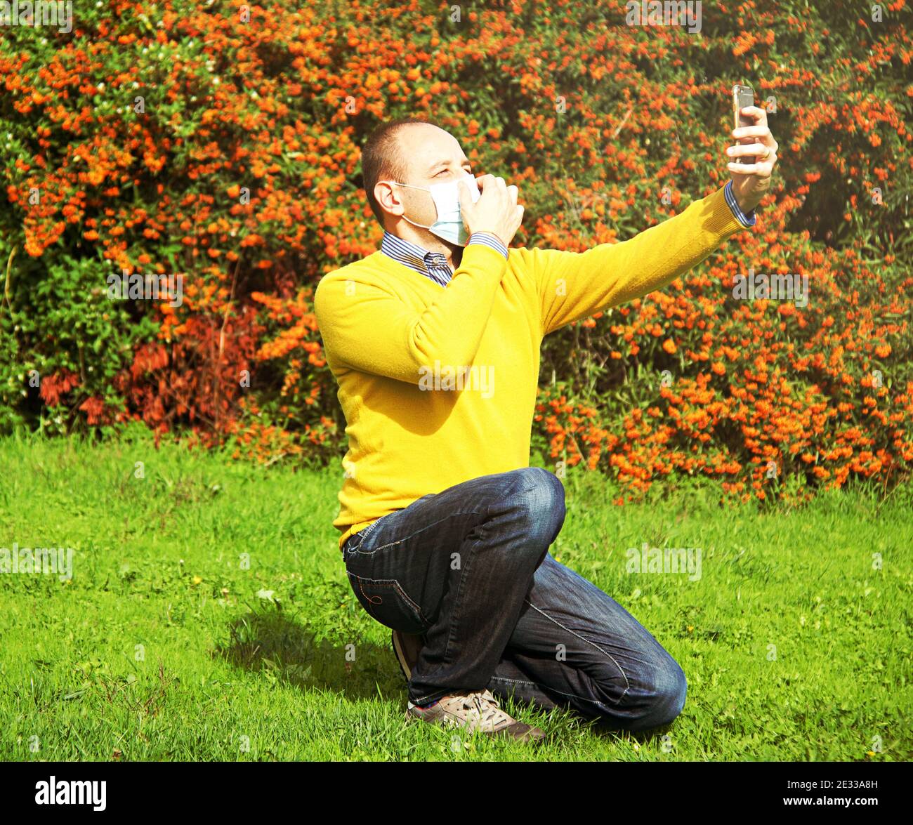 shot of a mid age business man in a park,  wearing a surgical mask while video calling home, concept of social distance and 'new normal' with Corona V Stock Photo