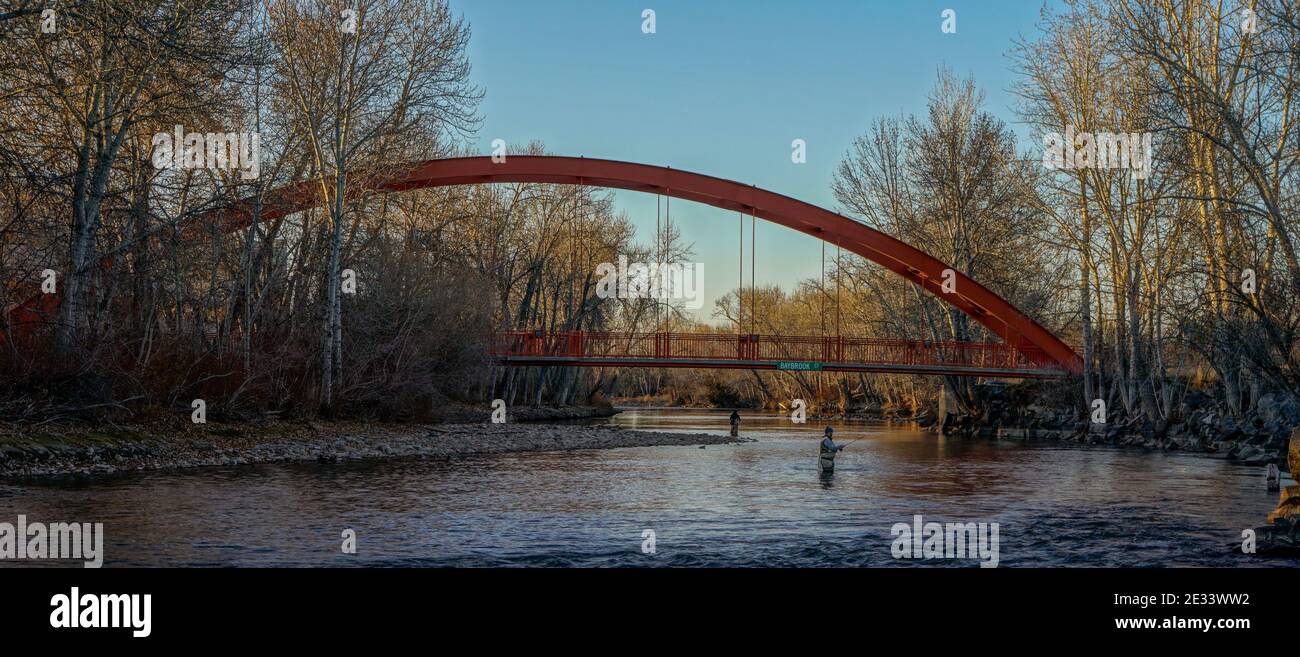 Two men fishing in Idaho's Boise River below the Baybrook Court  pedestrian bridge on a winter afternoon. USA Stock Photo