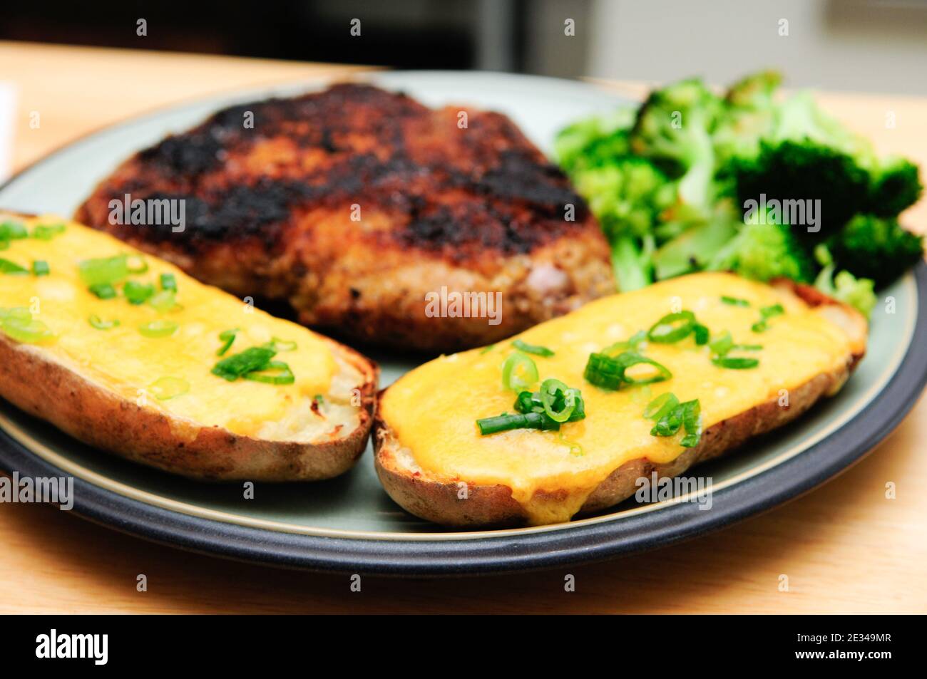 Closeup shot of tasty meat and potatoes with cheese and greens Stock Photo