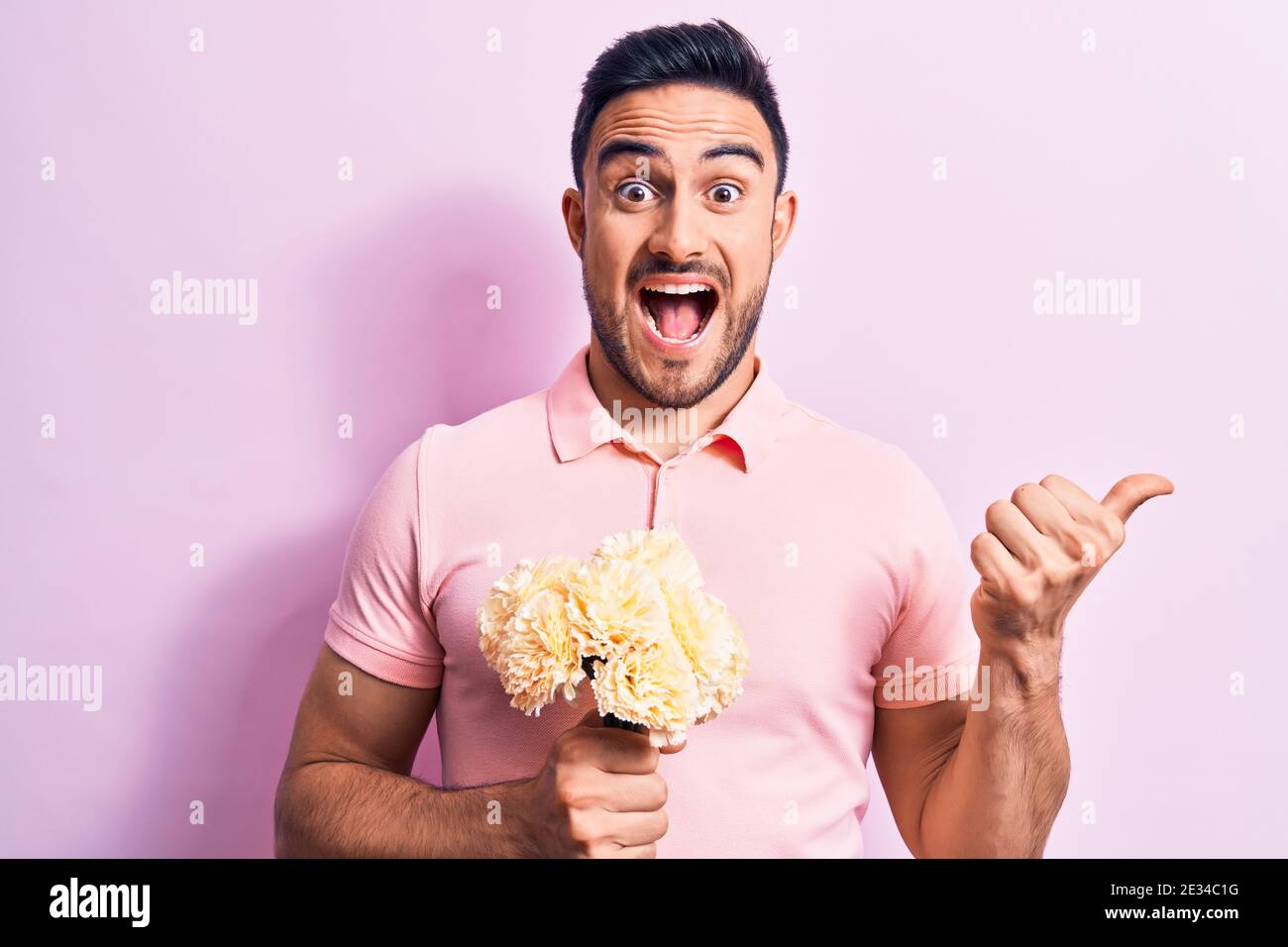 Young handsome romantic man with beard holding bouquet of flowers over ...