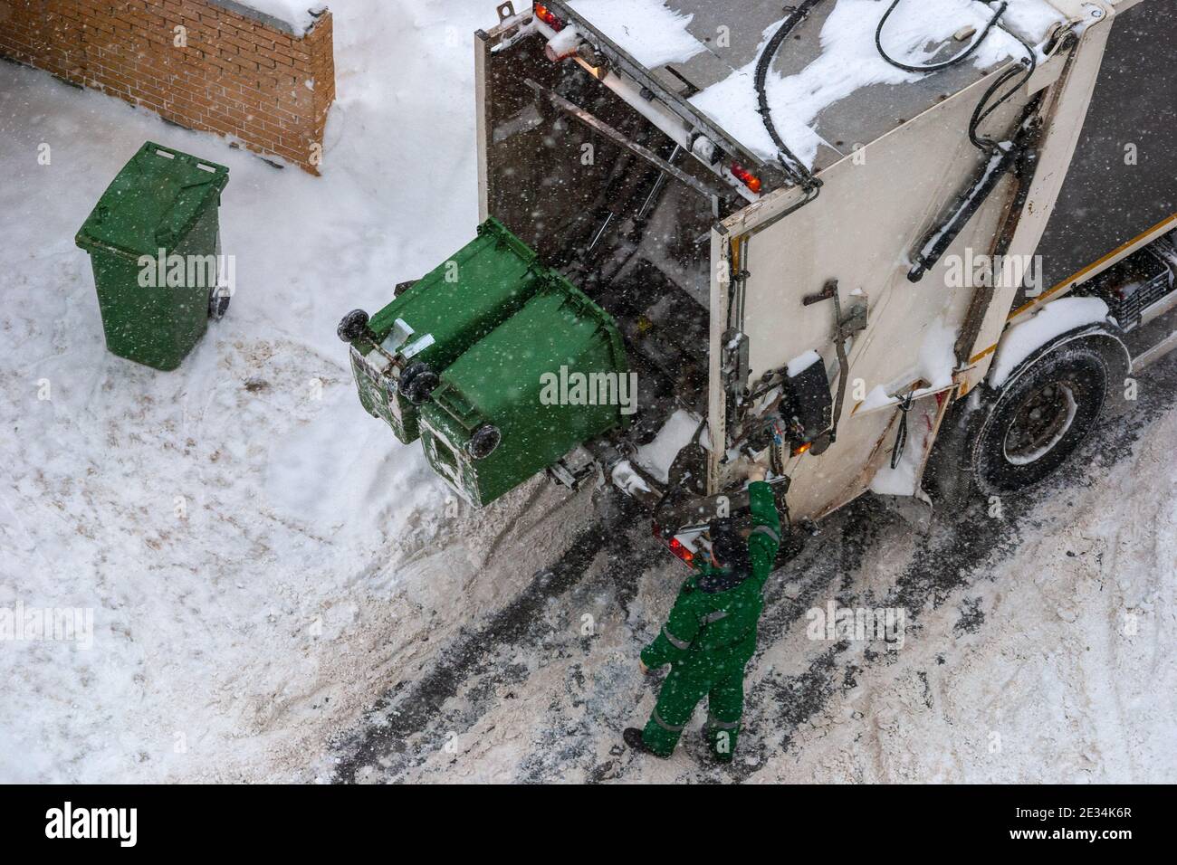 trash pickup in winter - garbage collector loading garbage truck, high angle view Stock Photo