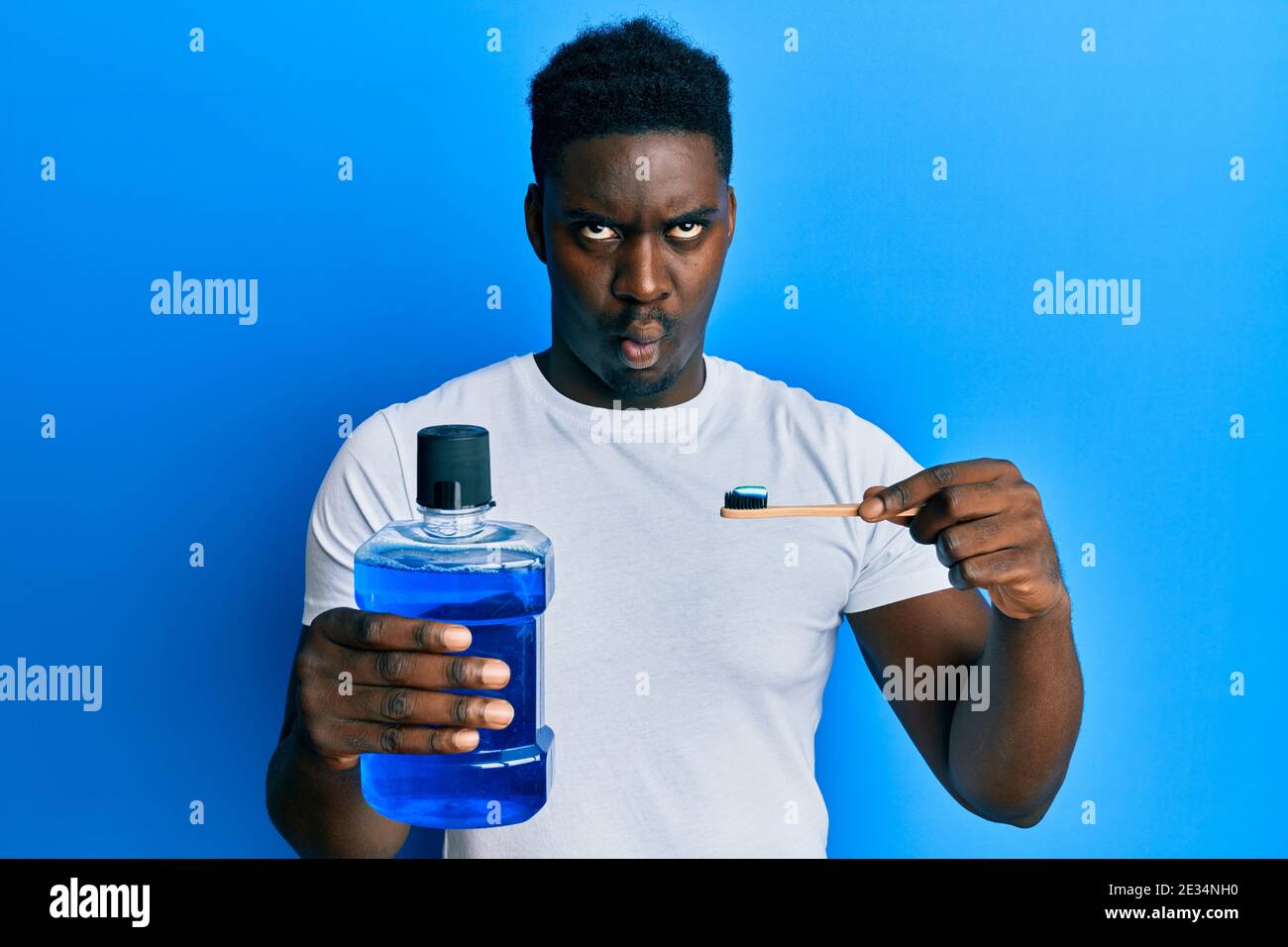 Handsome black man holding mouthwash and toothbrush for fresh breath